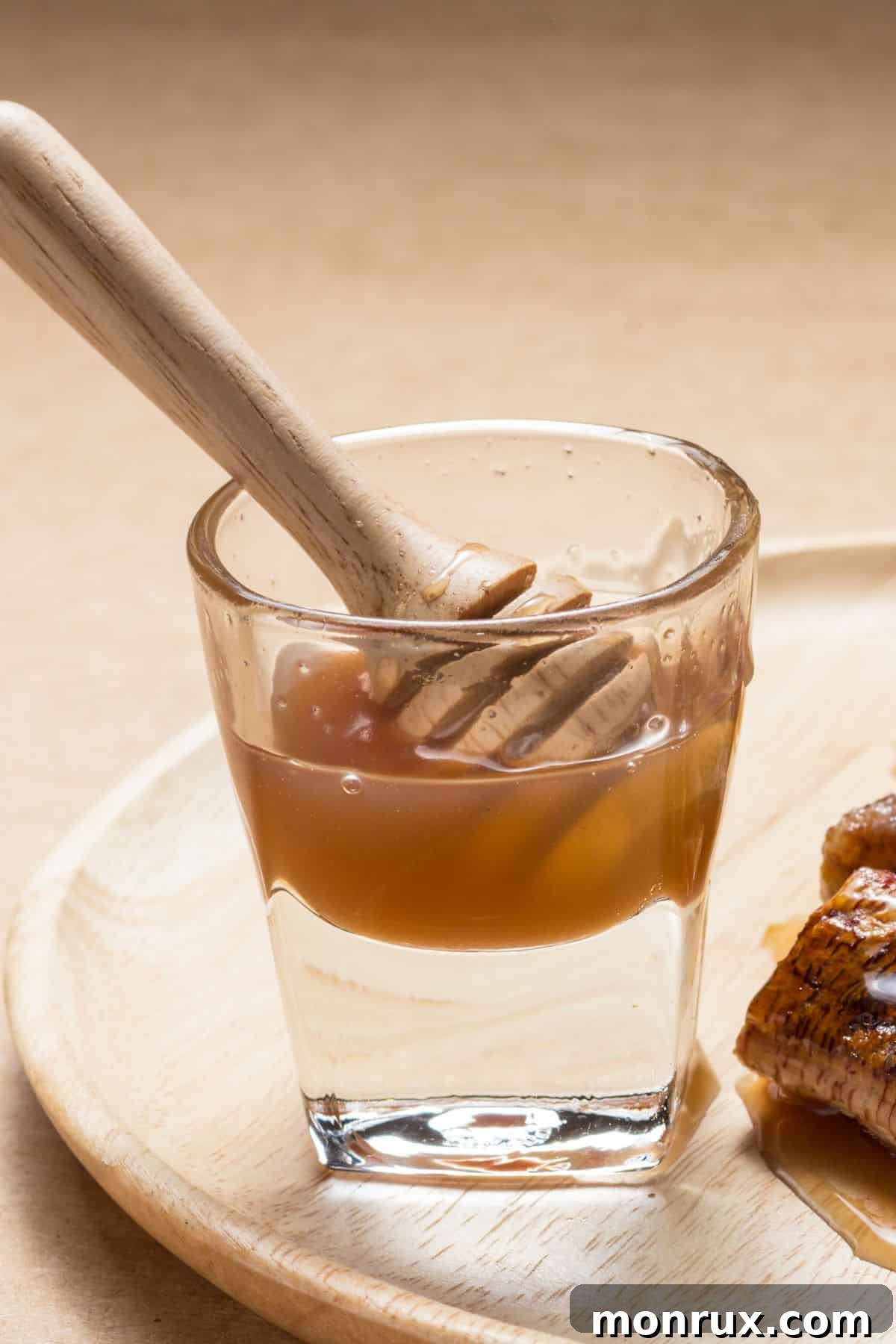 Clear glass container with coconut nectar on wooden surface.