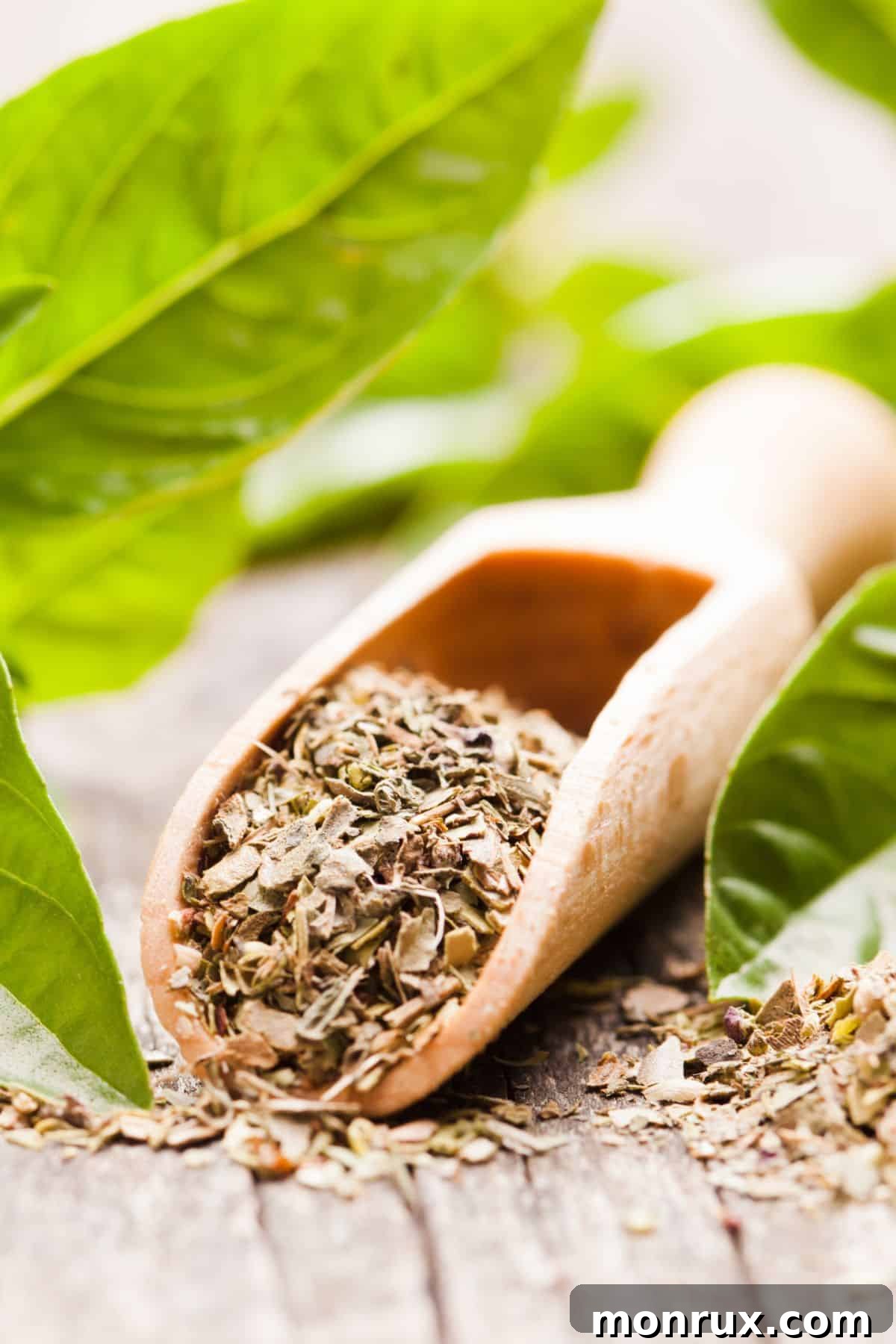 Scoop of dried basil with fresh basil in background, illustrating the topic of basil substitutes.