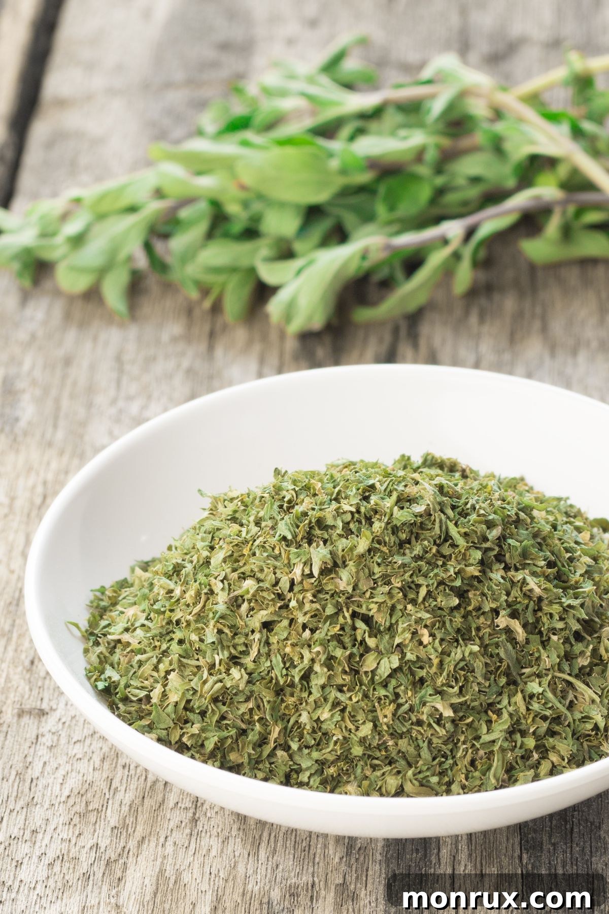 Bowl of dried marjoram on a wooden surface, suggesting its use as a dried basil alternative.