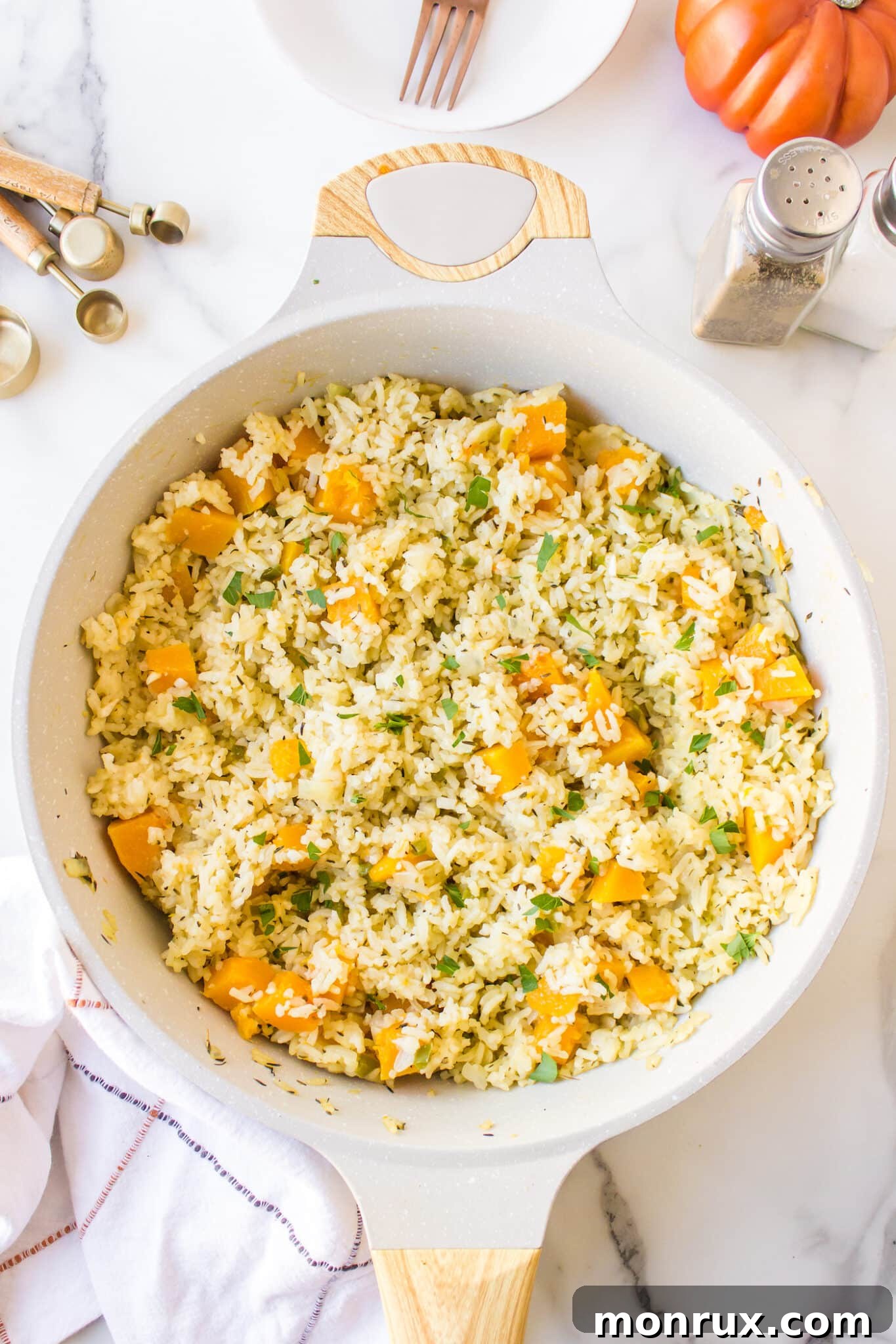 Cooked pumpkin rice simmering in a covered pan, showing the steam and tender texture as it absorbs the liquid.