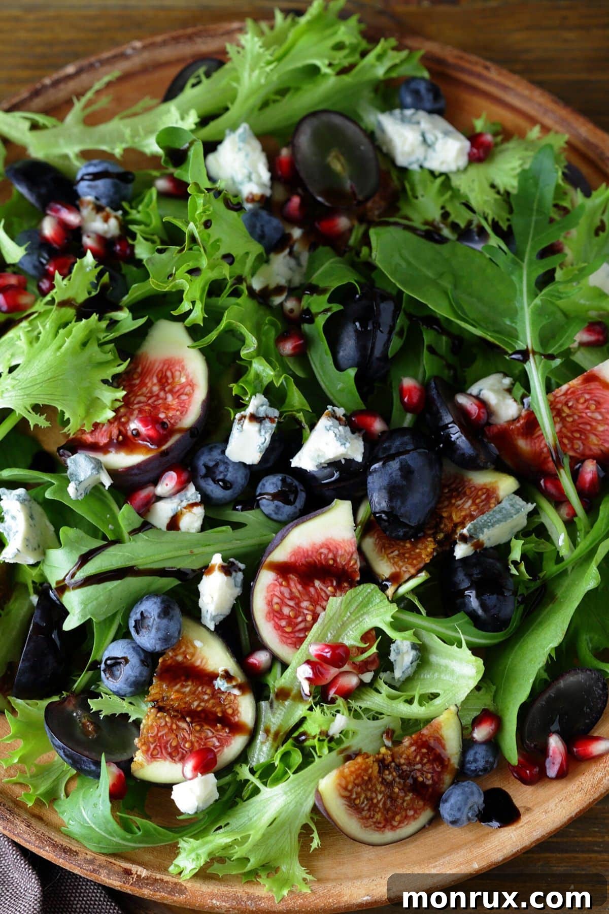 A leafy green salad with figs and blueberries and a balsamic drizzle.