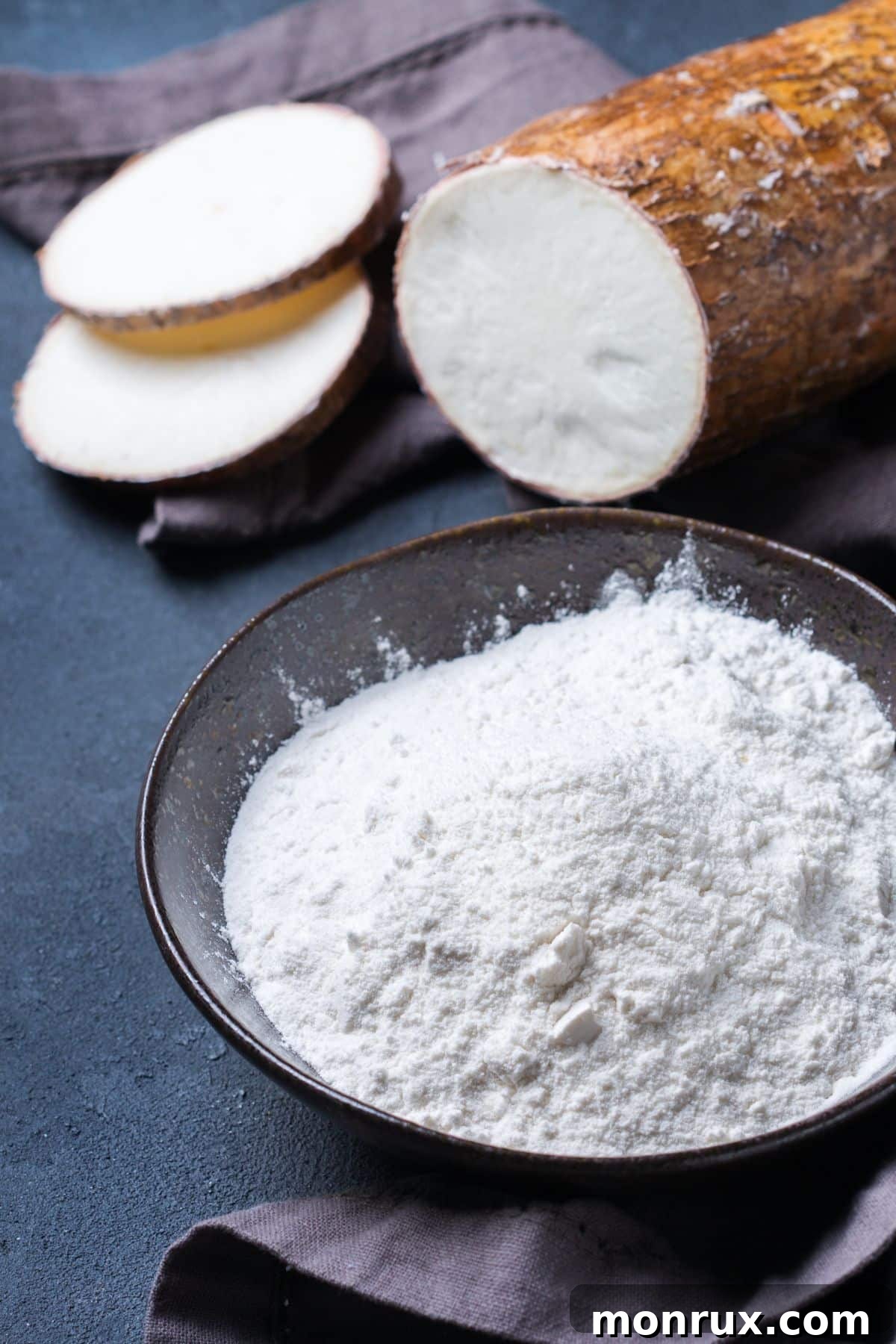 Bowl of fine cassava flour alongside whole cassava root, illustrating its origin and refined texture.