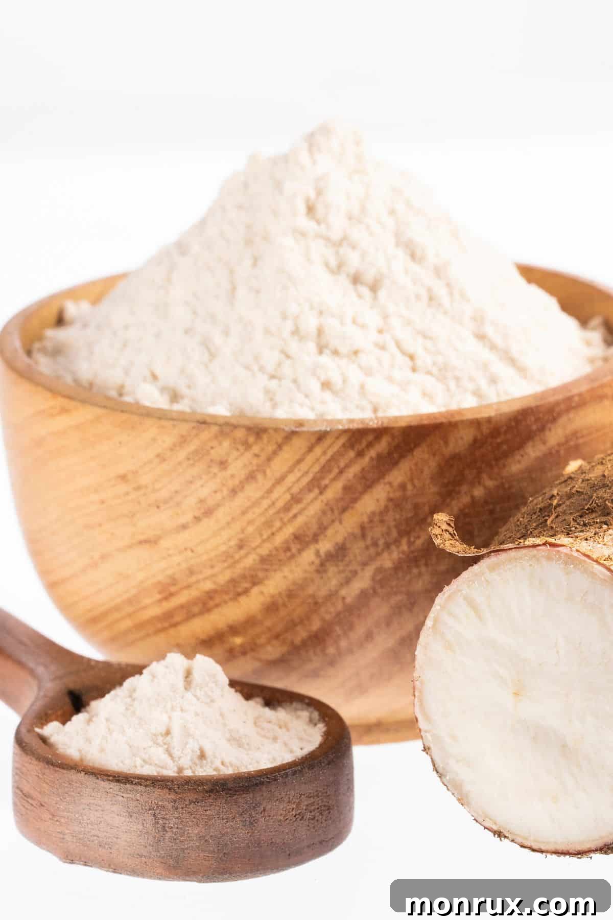 Bowl and spoonful of pure white arrowroot flour against a clean white background, emphasizing its refined, powdery texture.