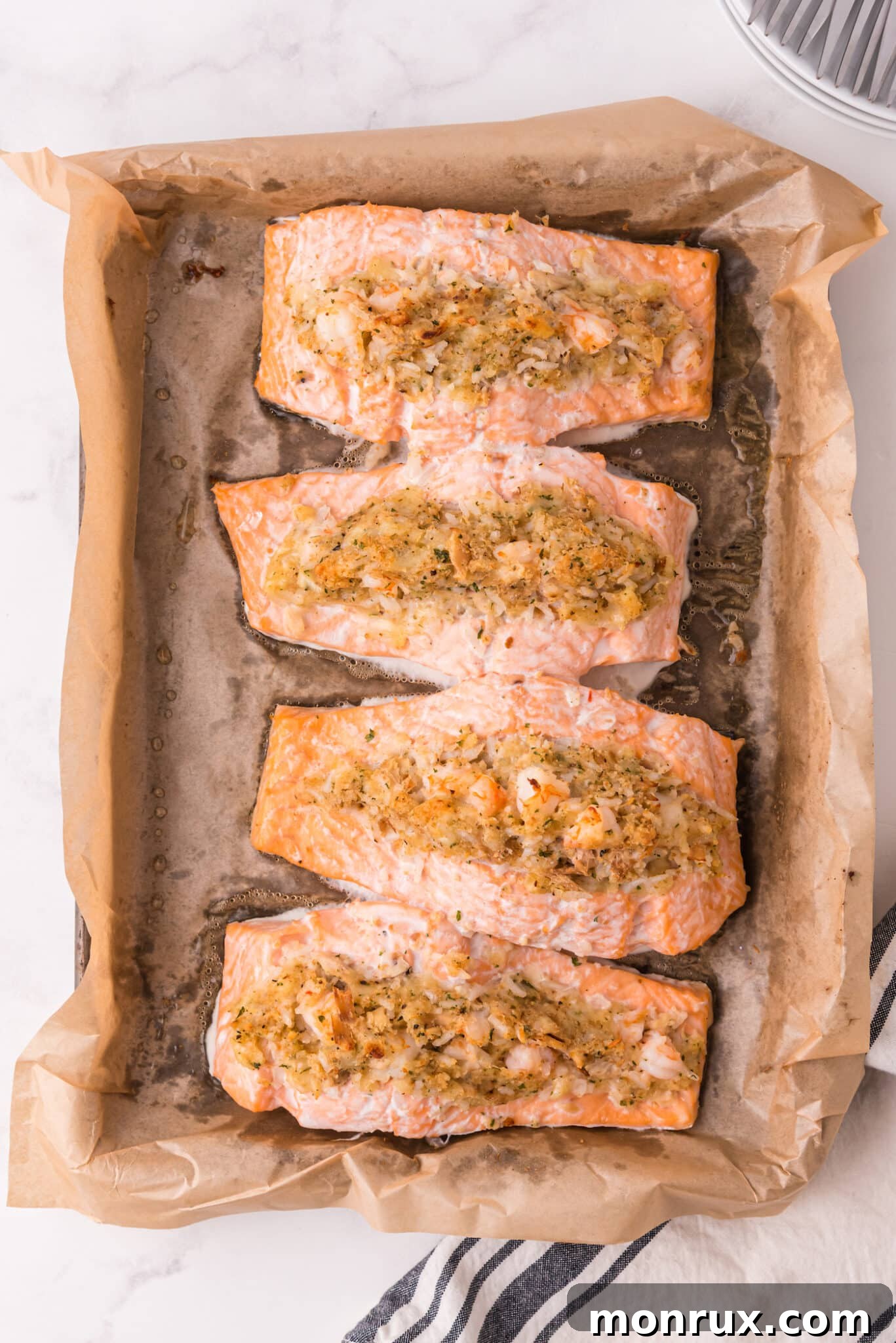 Golden-brown, baked, stuffed salmon fillets nestled in a parchment-lined baking dish, ready to be served.