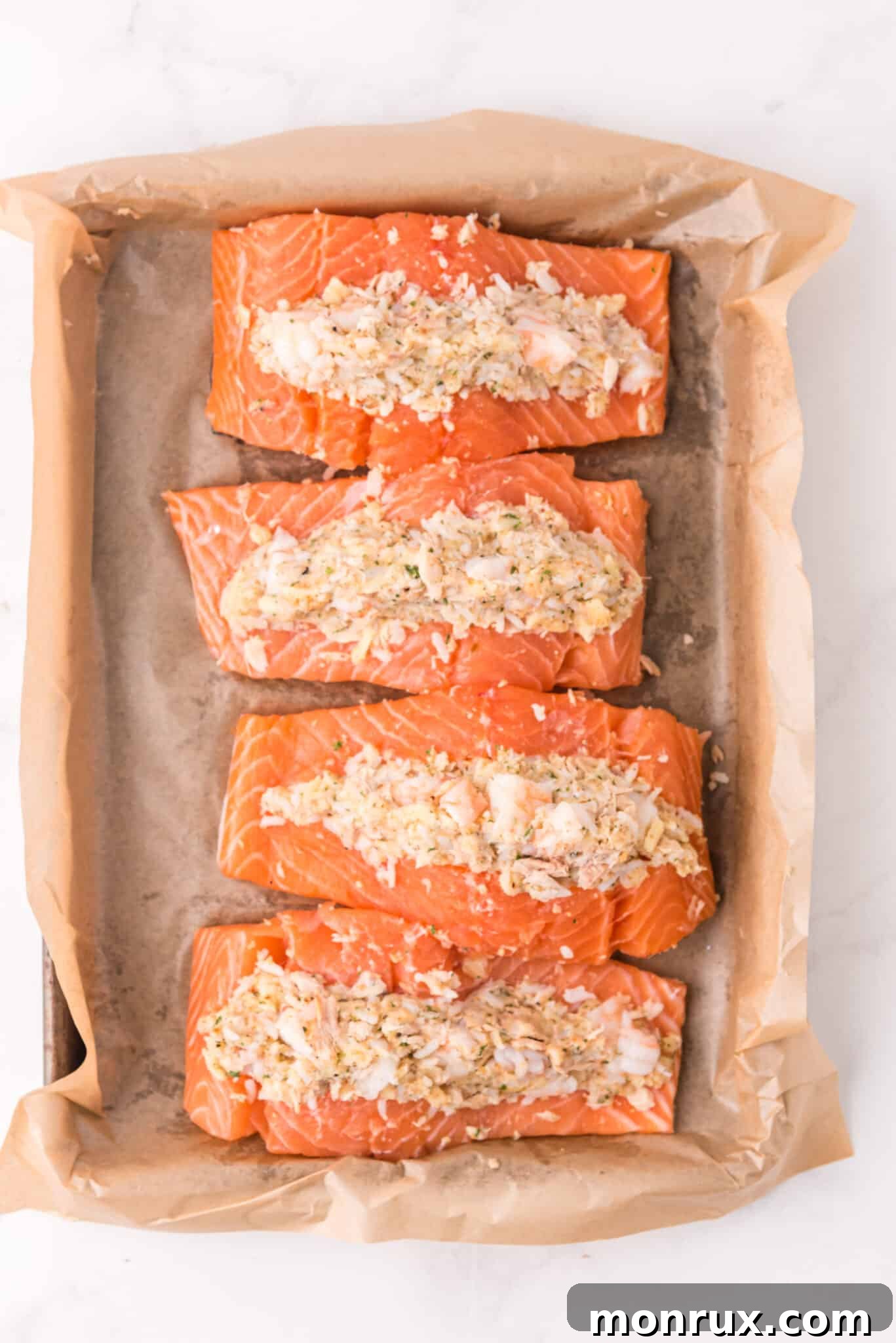 Stuffed salmon fillets perfectly arranged on a baking sheet, glistening and ready for the oven.