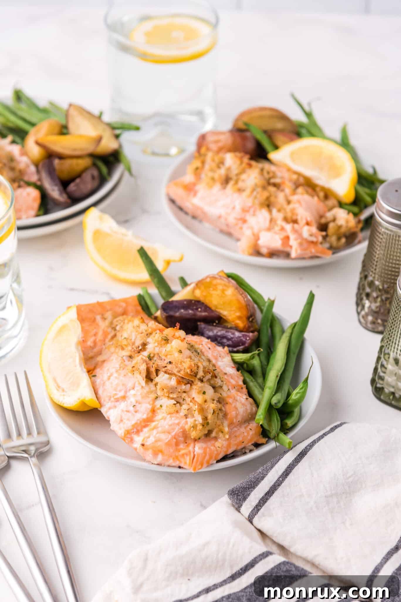 Plated stuffed salmon served with a vibrant side of green beans and roasted potatoes on white dinner plates.