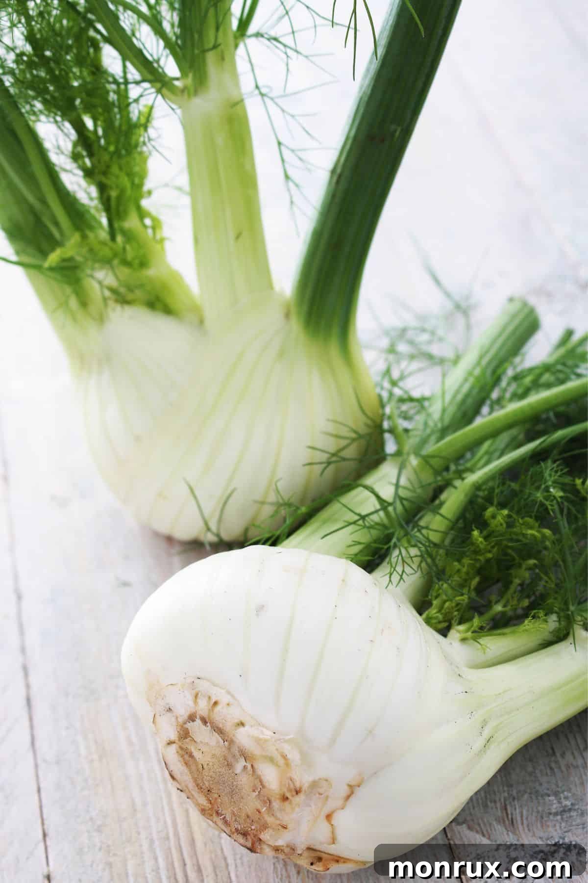 Whole fennel bulbs on wooden surface.