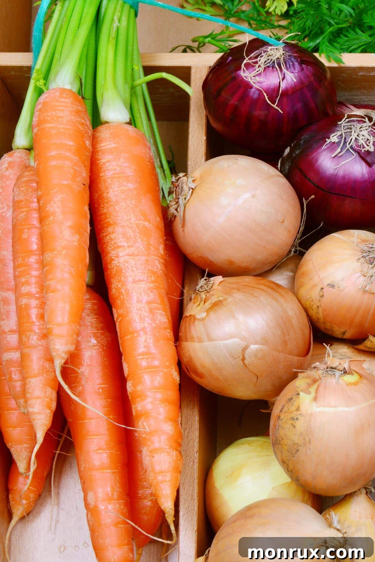Whole carrots and onions in a wooden container.