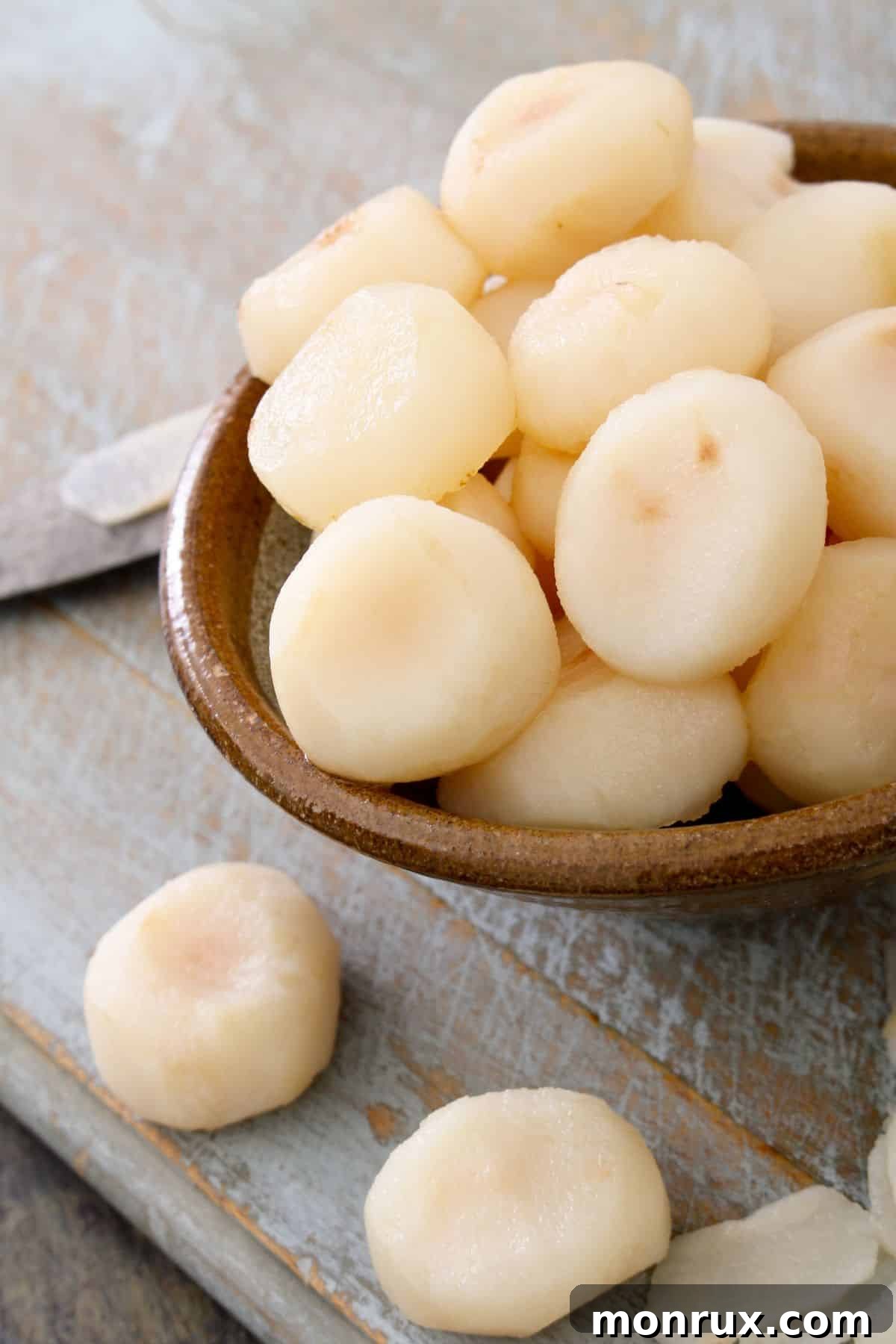 Bowl of water chestnuts on wooden surface.