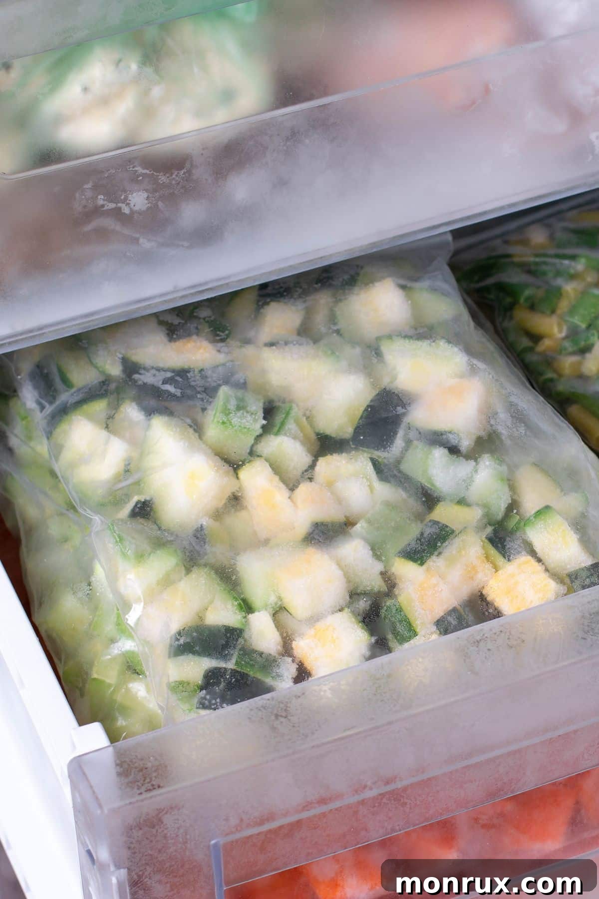 Diced zucchini frozen in a baggie in a freezer drawer, demonstrating proper frozen food storage.
