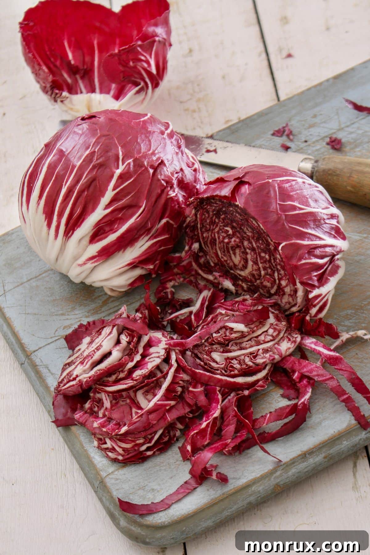 Halved and whole radicchio on wooden cutting board.