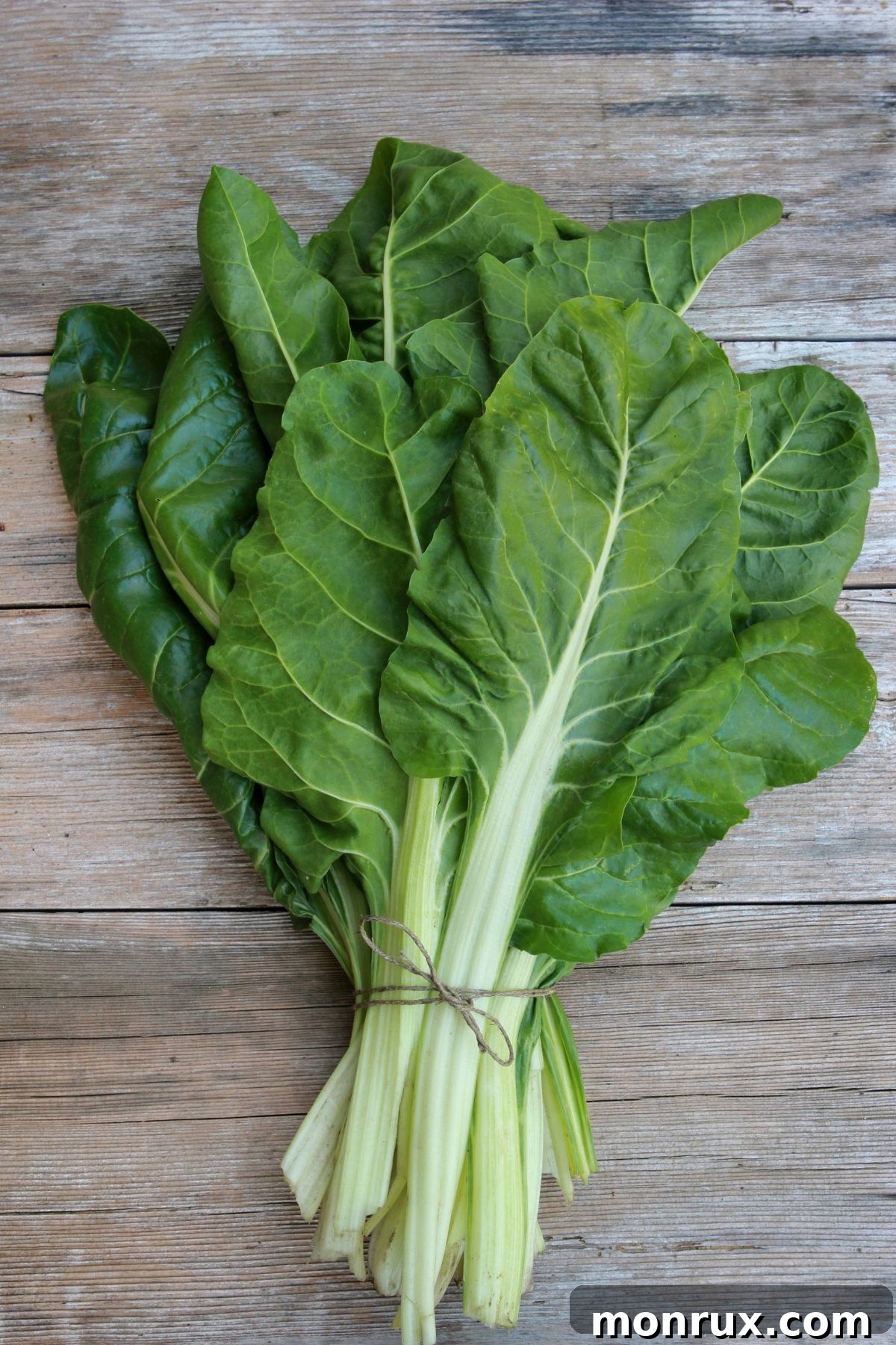 Tied bunch of chard on wooden surface.