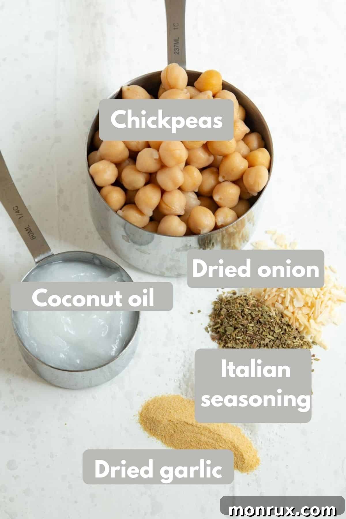 A selection of fresh ingredients including chickpeas, coconut oil, Italian seasoning, garlic powder, and salt laid out for roasted chickpea preparation.