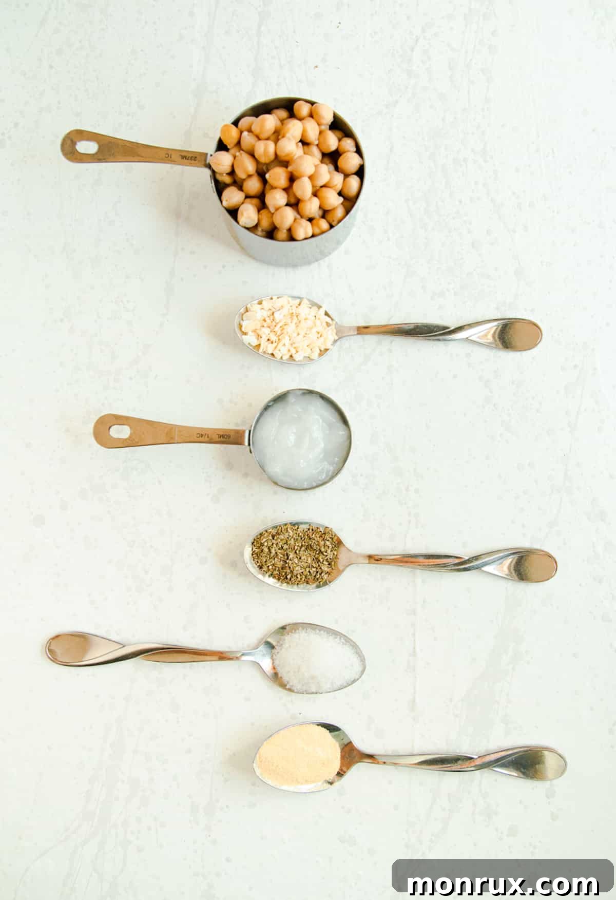 A close-up shot of chickpeas coated in a flavorful blend of Italian seasoning, garlic powder, and dried onion, ready for roasting.