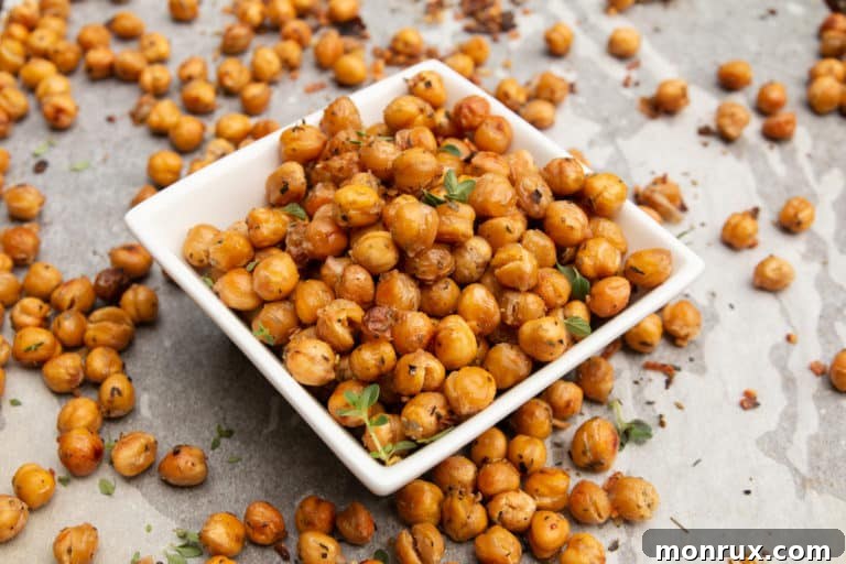Roasted chickpeas in a white bowl, garnished with fresh herbs, ready to be served.