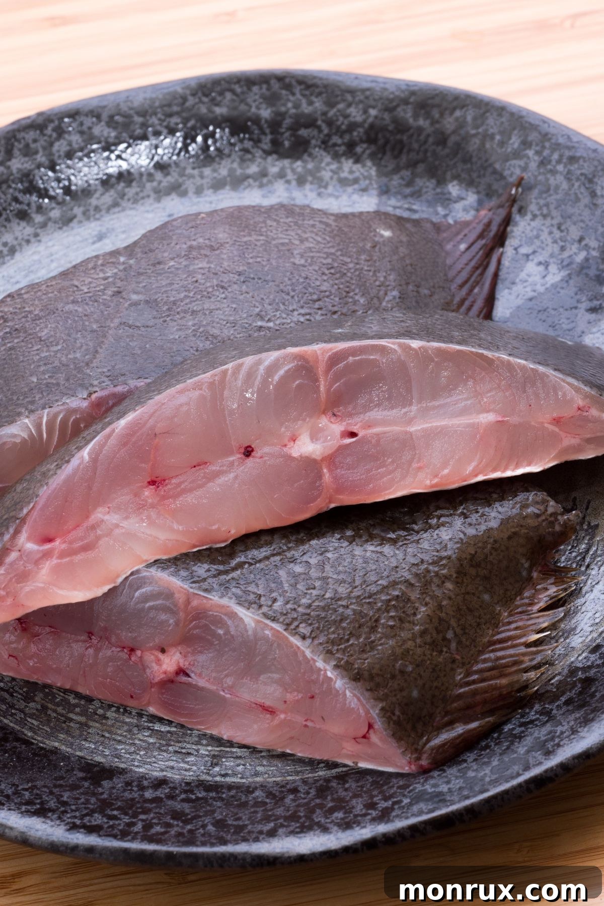 Flounder fillets on slate plate on wooden surface.