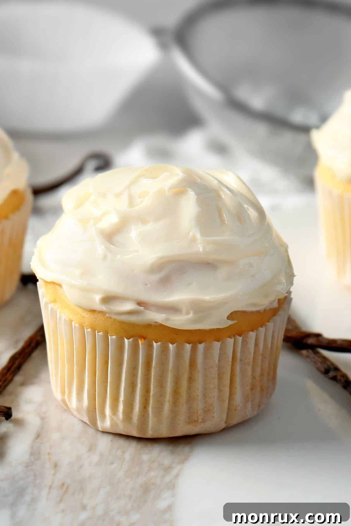 A vanilla cupcake topped with vanilla frosting on a marble counter, symbolizing healthy indulgence.