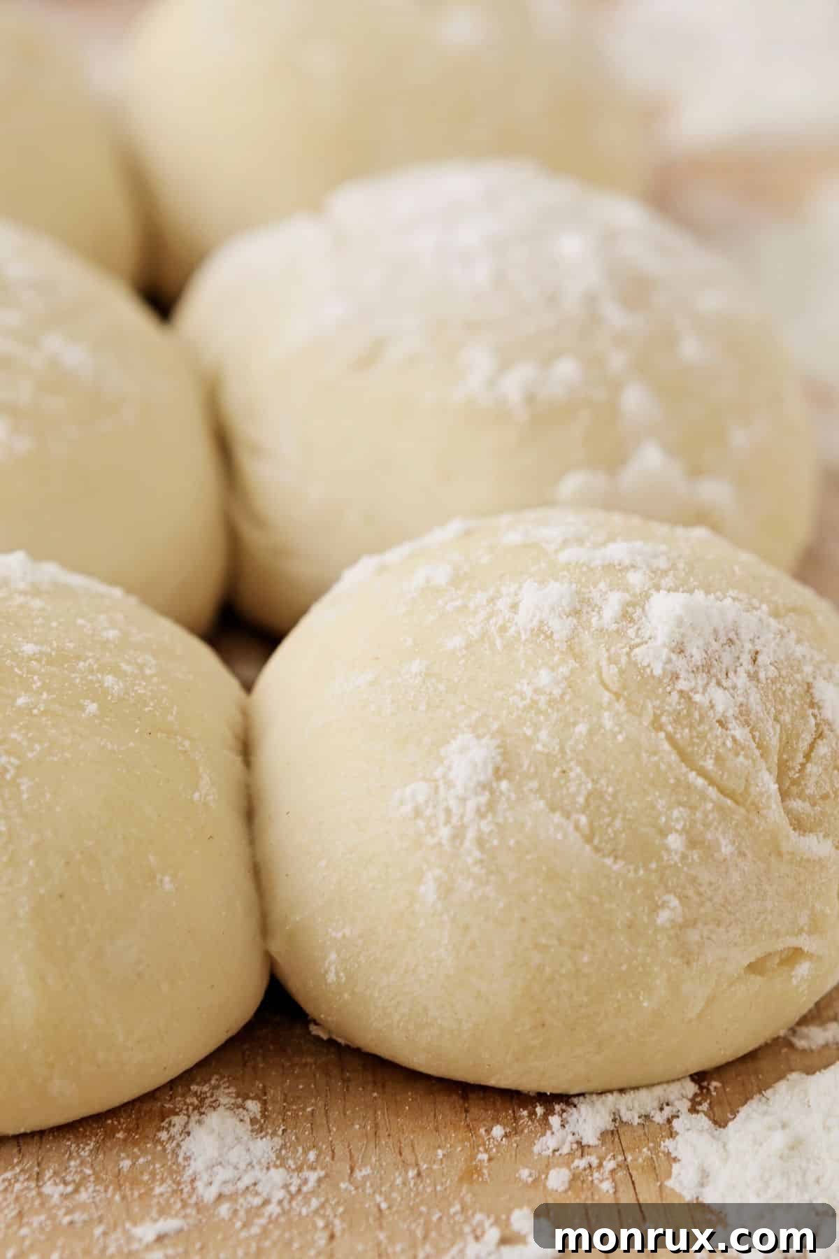 Perfectly shaped gluten-free dinner rolls resting on a wooden board, ready for their second proof.