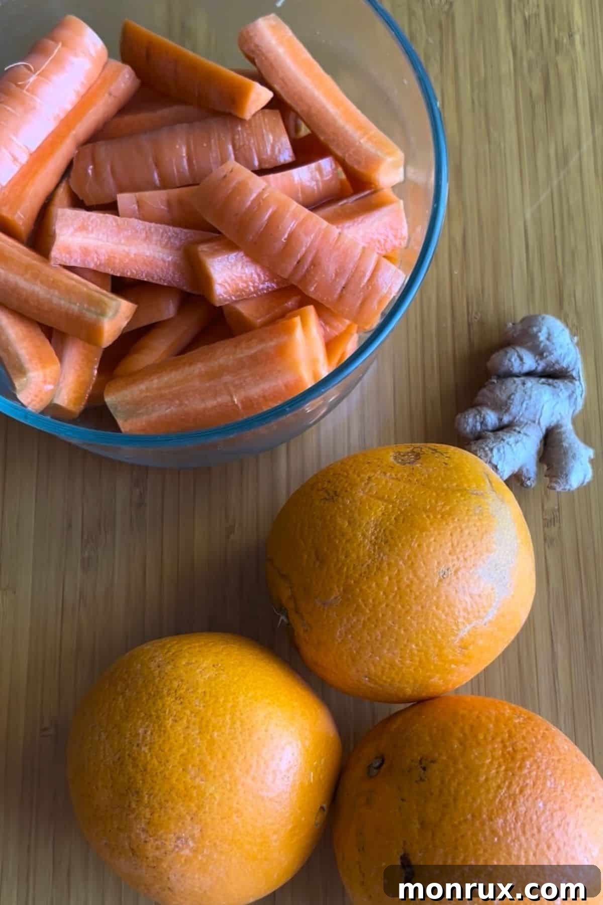 Ingredients for making carrot, orange, and ginger juice, including whole carrots, oranges, and a knob of ginger.