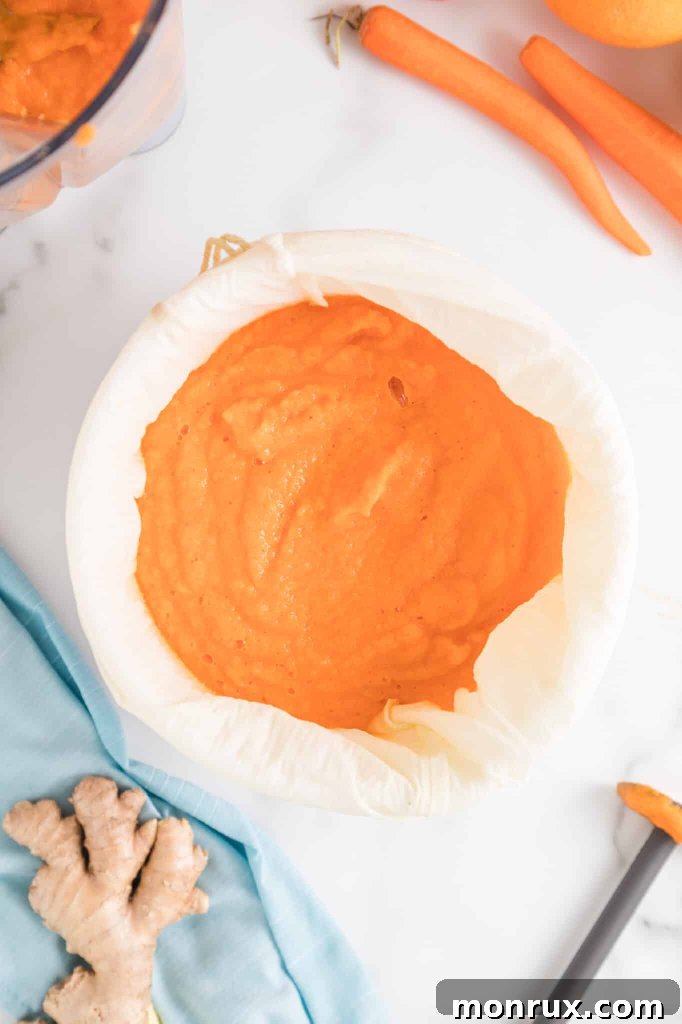 Straining the blended juice through a nut milk bag over a bowl.