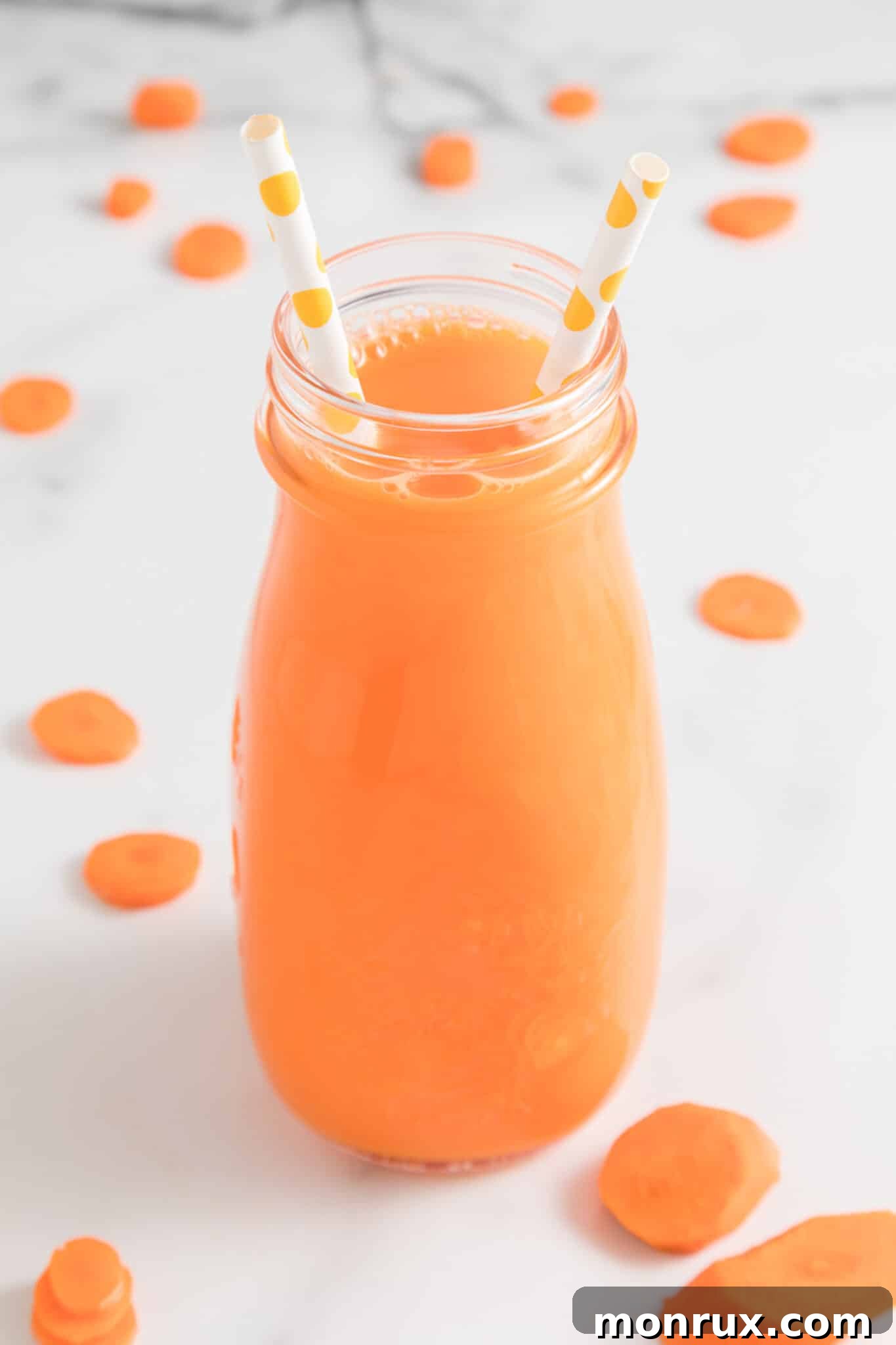 Finished Vitamix carrot juice in a jar with straws, ready to be served.