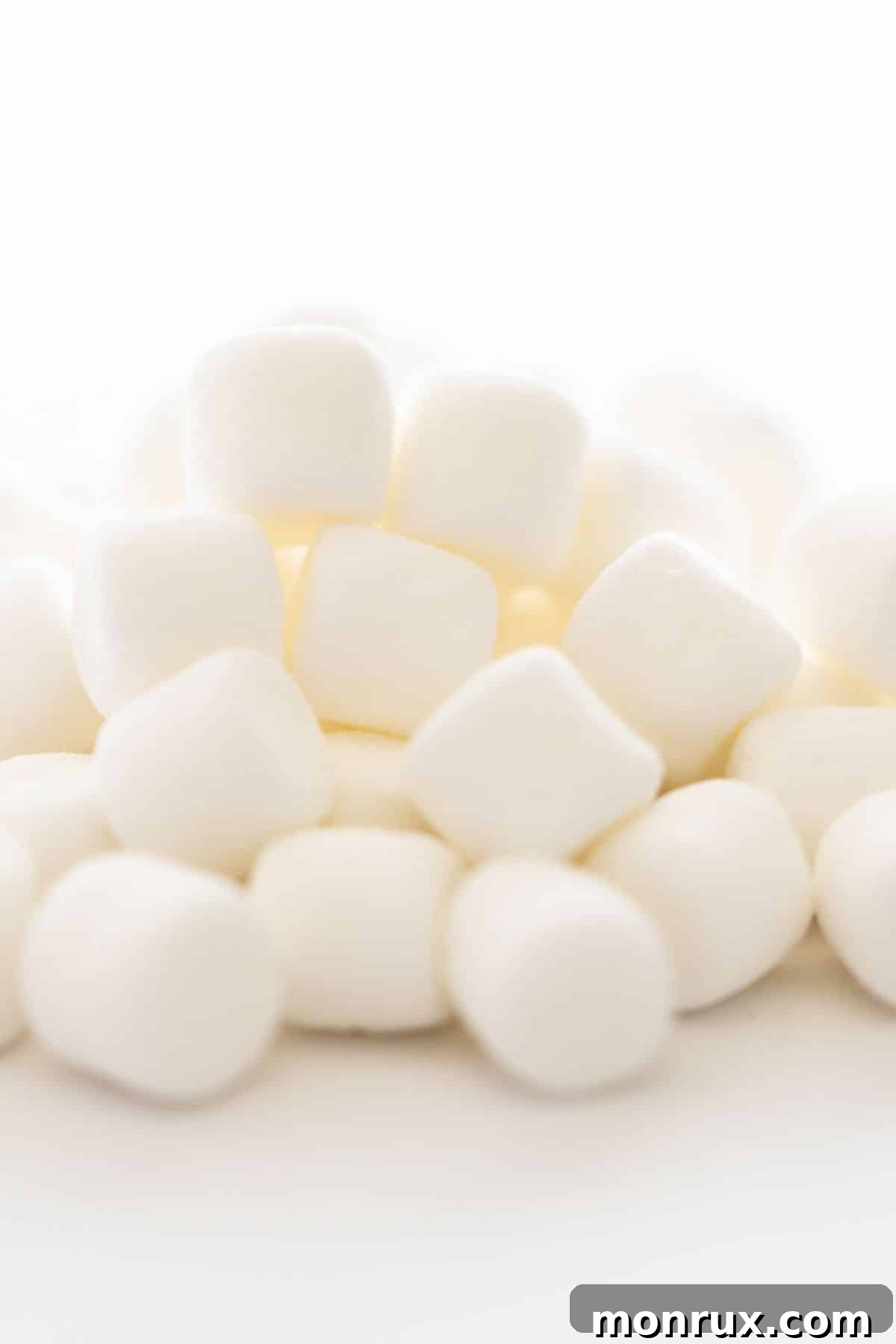 A pile of regular marshmallows on a white background.