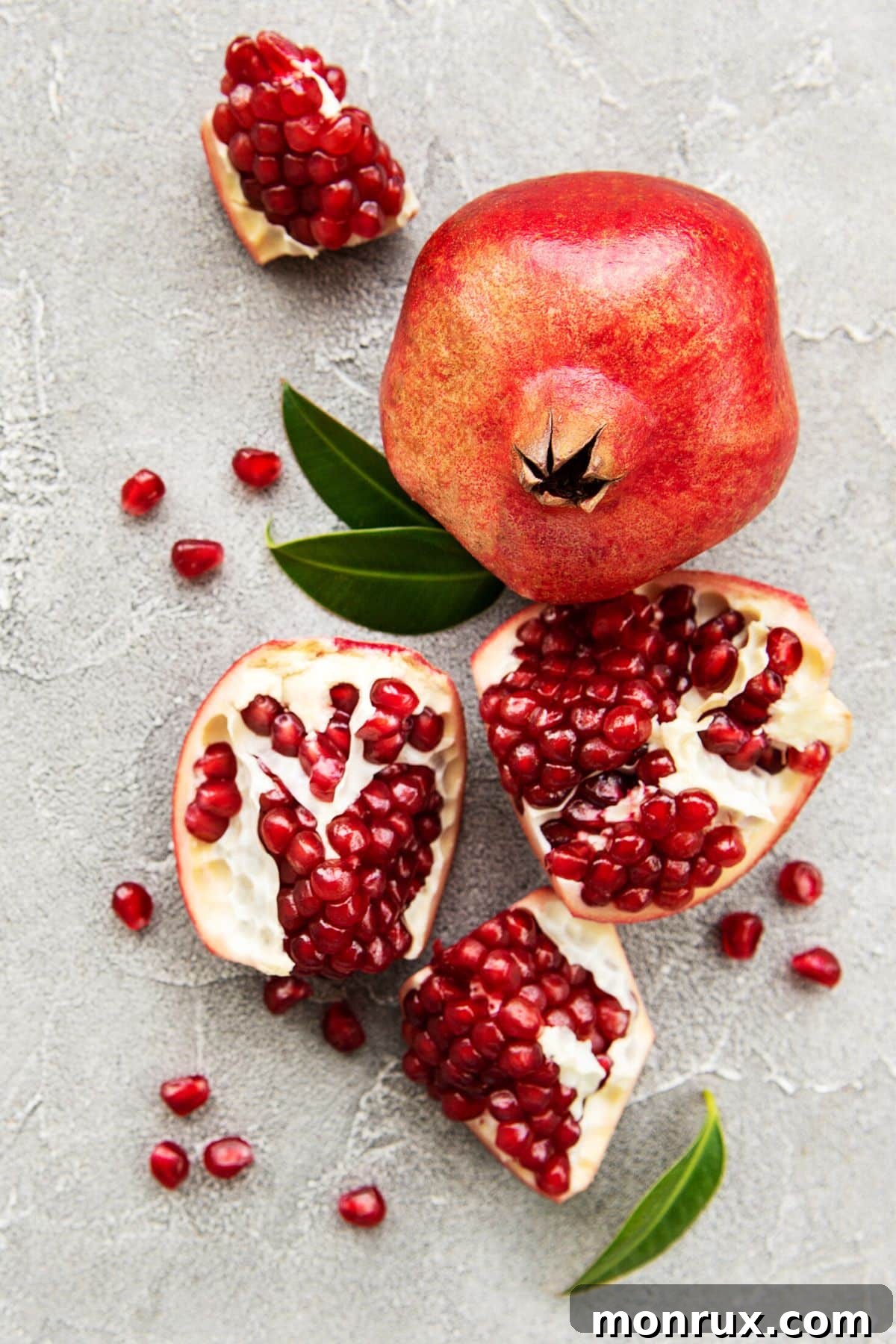 A whole pomegranate next to one that has been sectioned.