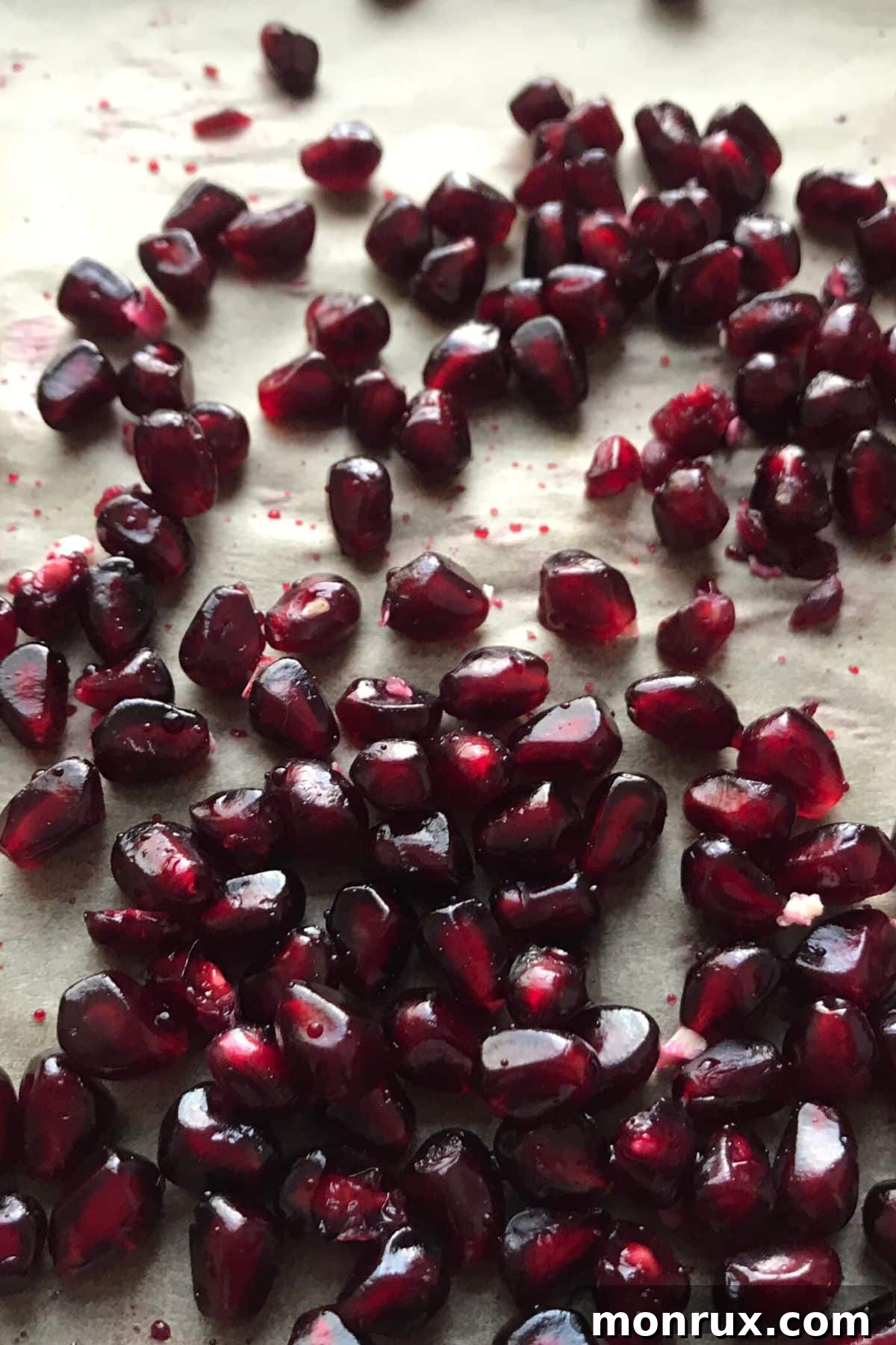 Deep, dark pomegranate arils on a white background, highlighting their rich color.