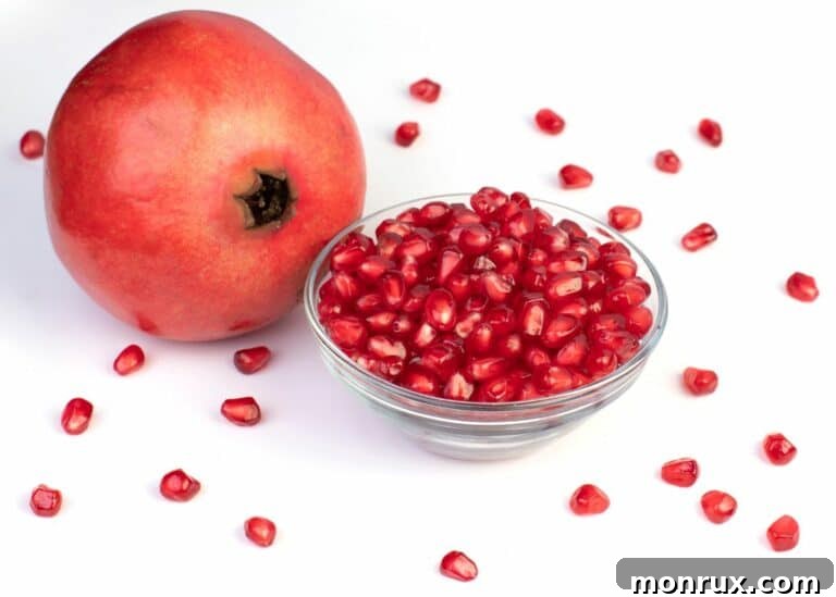 A whole pomegranate next to a small glass bowl of seeds.