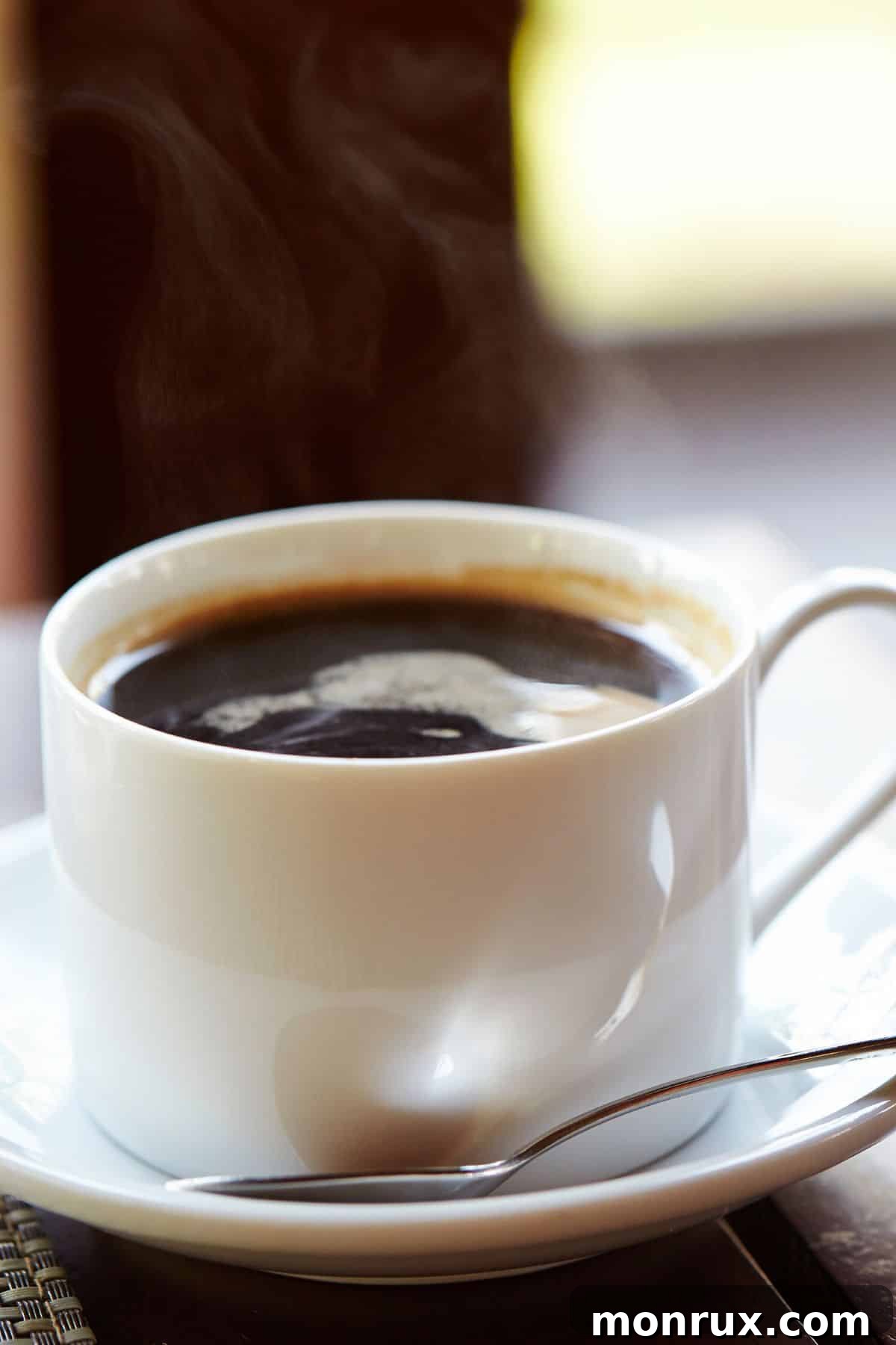 A small mug of maca coffee on a saucer with a spoon, highlighting its creamy texture.