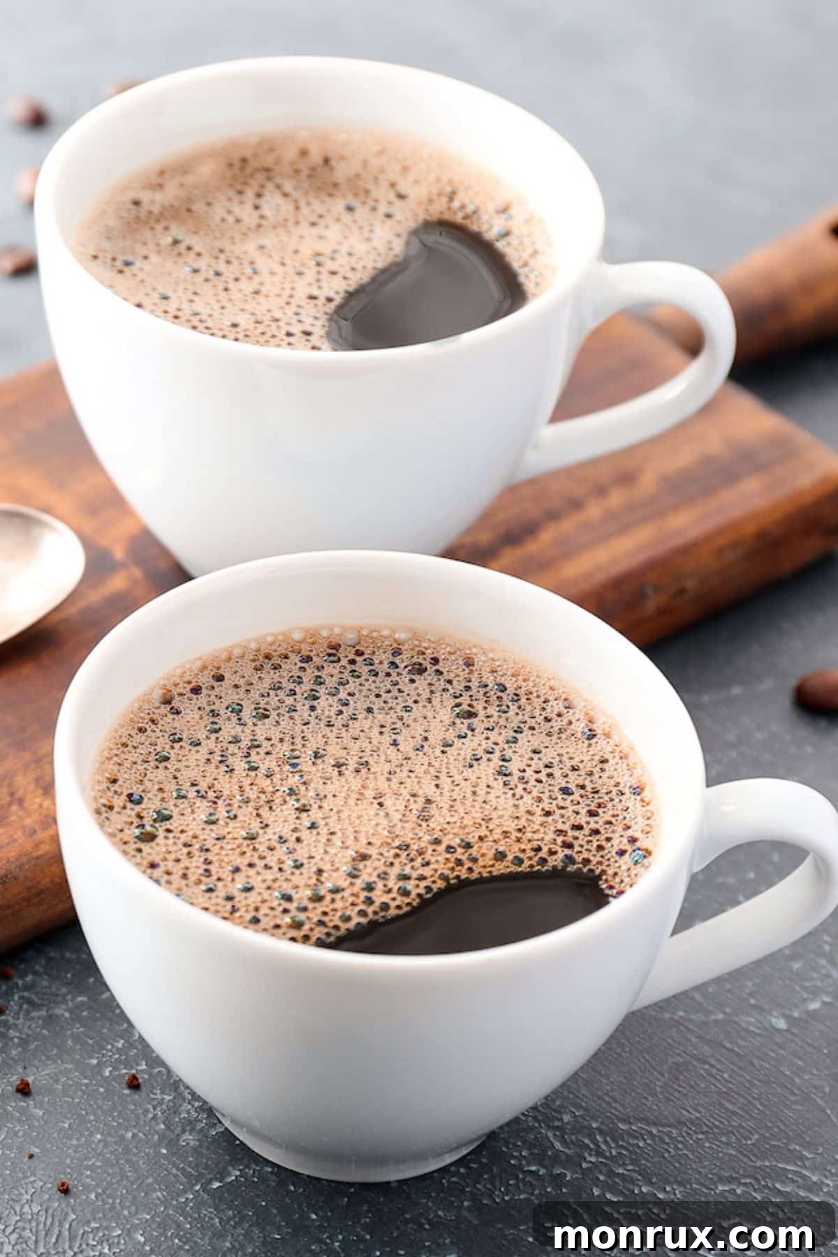 Two white mugs filled with frothy maca coffee on a wooden table, invitingly served.