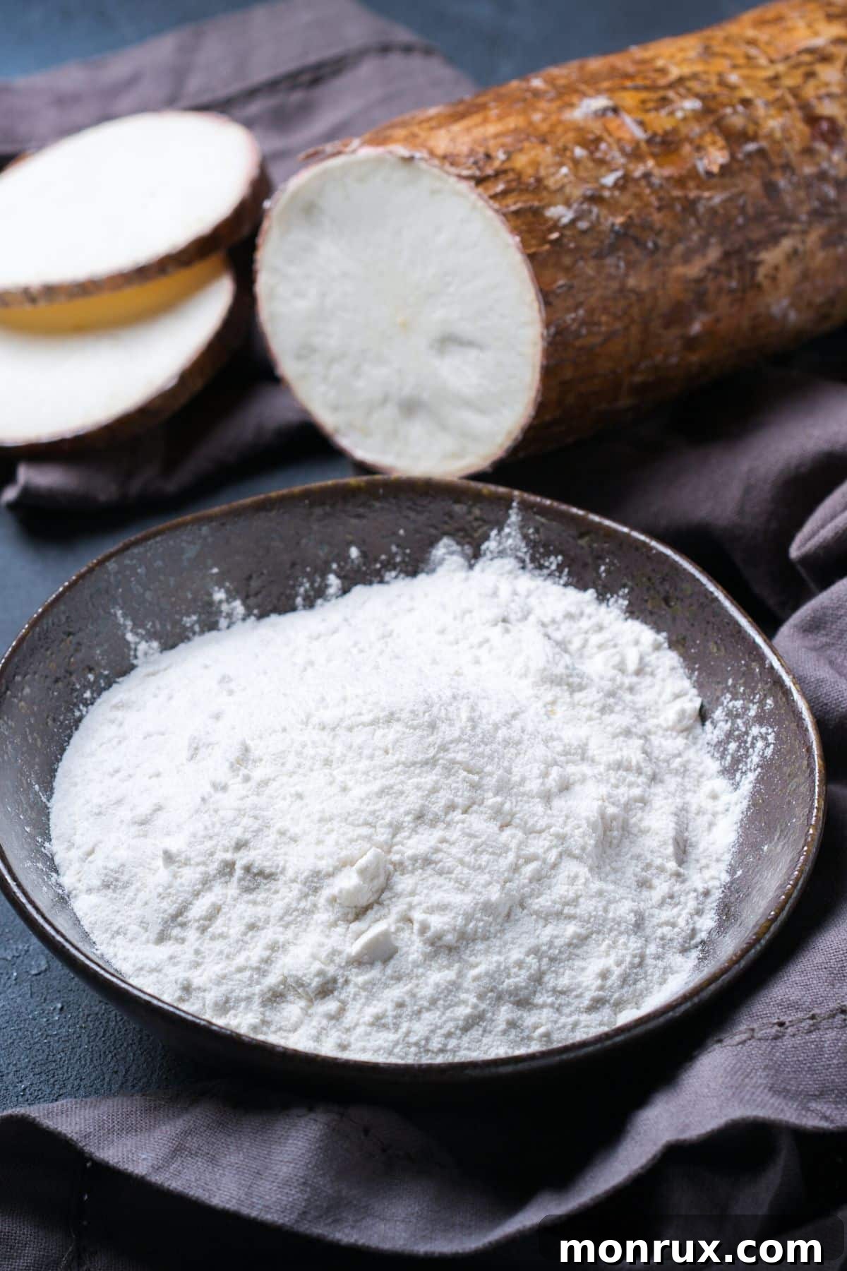 Fresh cassava root next to a bowl of fine tapioca starch, illustrating their raw and processed forms.