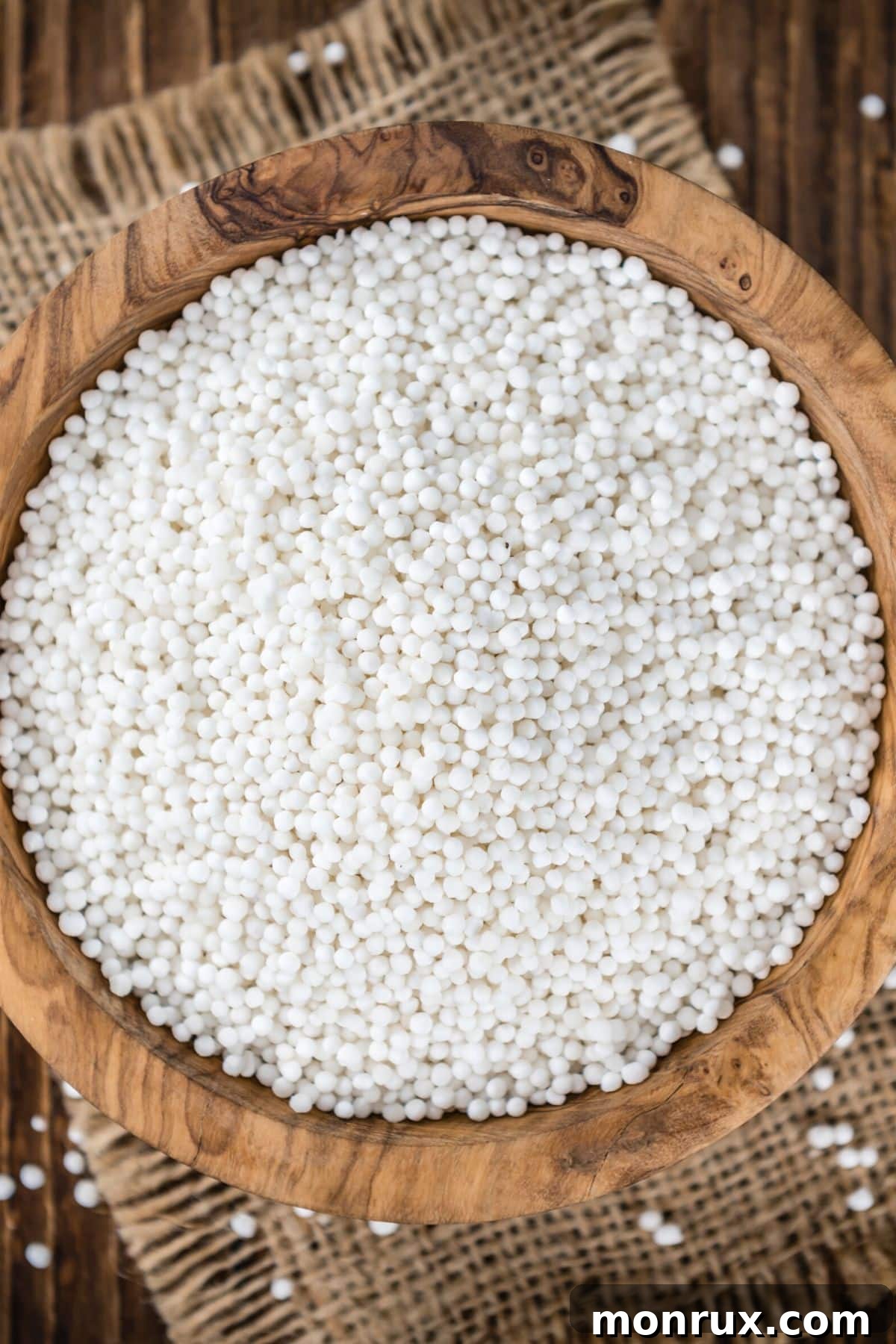 Tapioca pearls in a small bowl on a wooden table, ready for use in desserts or drinks.