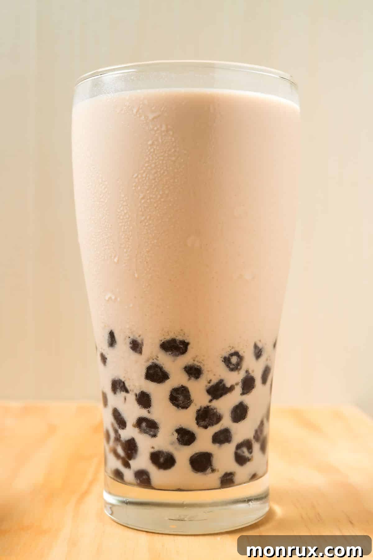 Refreshing coffee boba drink in a clear glass with a wide straw, showcasing tapioca pearls at the bottom.