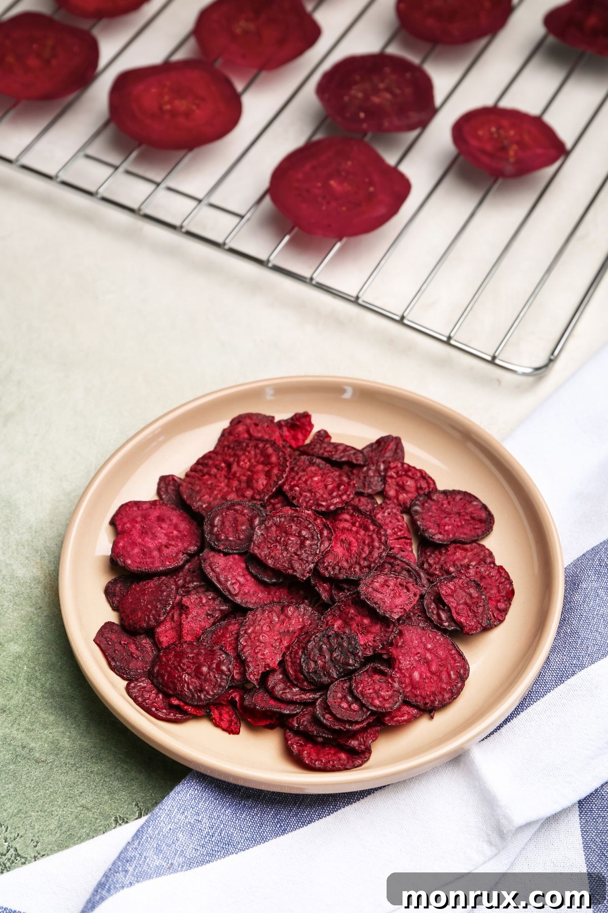 Crispy dehydrated beet chips elegantly arranged on a rustic brown plate, showcasing their vibrant color and inviting texture.