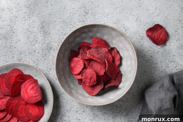 Dehydrated beet chips in two gray bowls, one with a pile of chips, the other with a smaller serving.