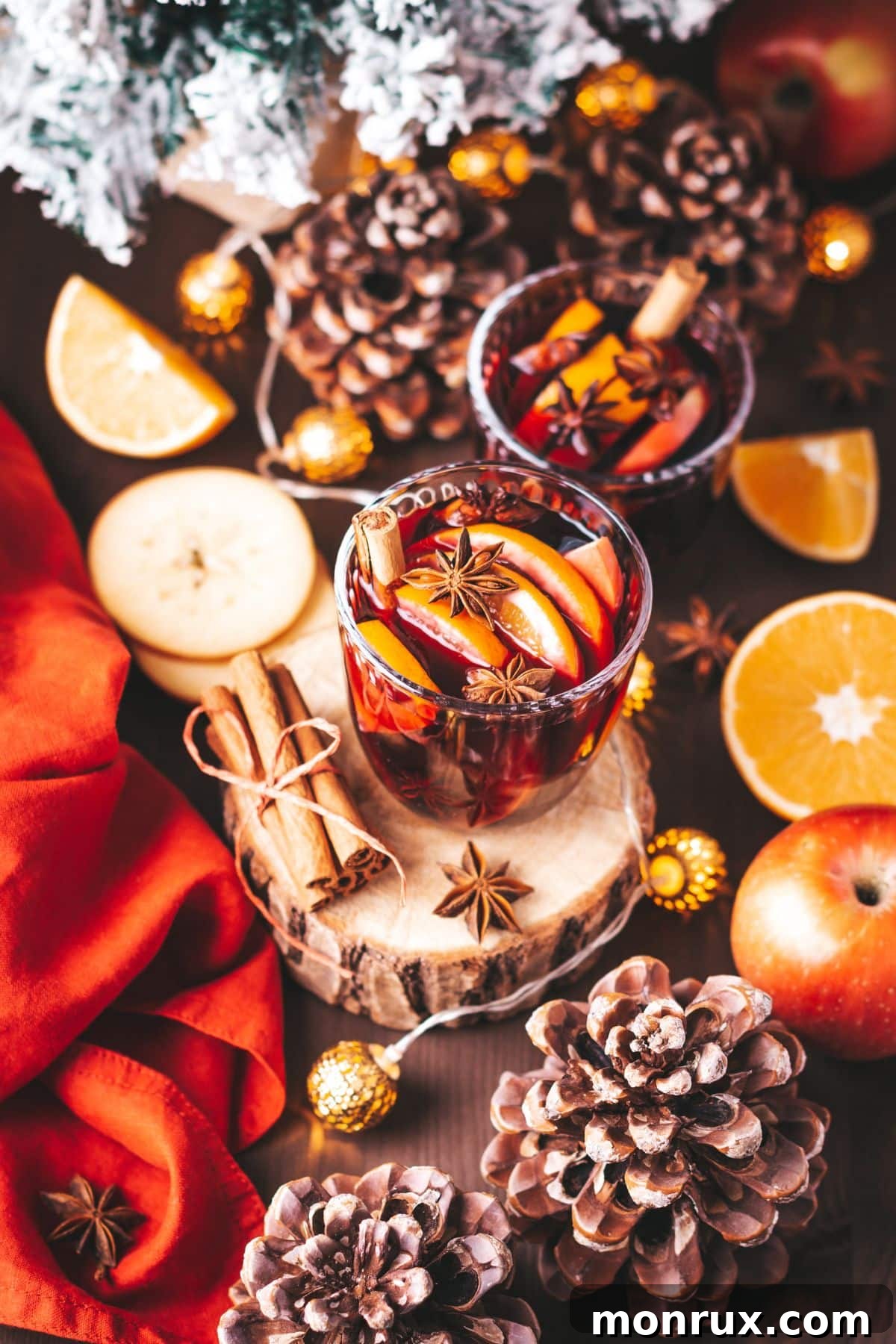 Two festive drinks garnished with oranges and cinnamon sticks, set on a wooden table with seasonal decor, perfect for clean holiday celebrations.