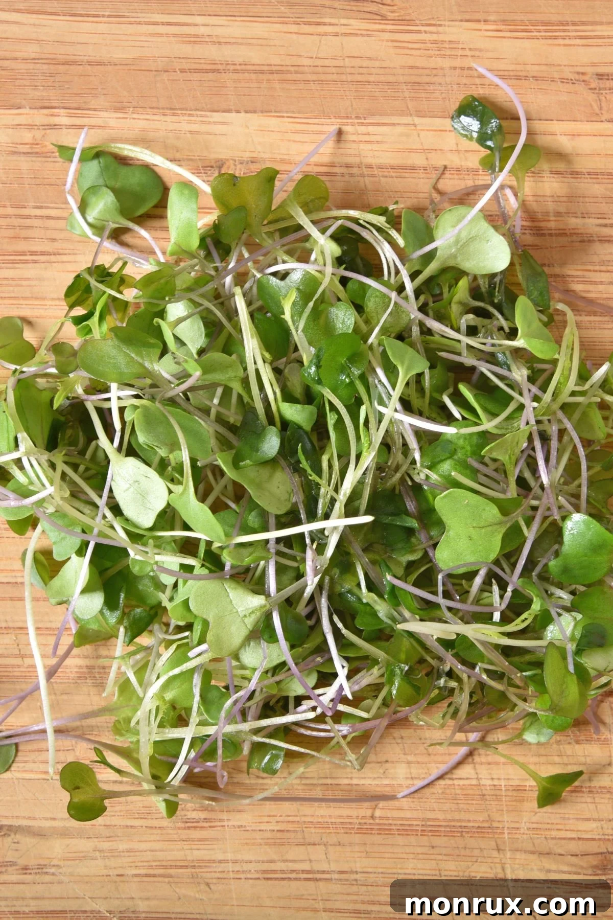 A generous bunch of freshly harvested kale microgreens artfully arranged on a rustic wooden cutting board.