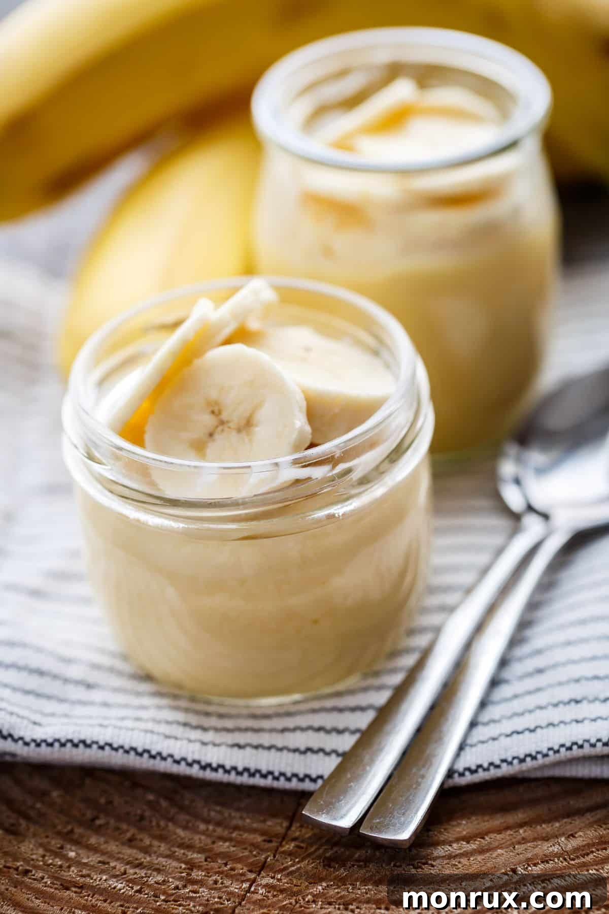 A bowl of creamy dairy-free banana pudding on a wooden table, garnished with fresh banana slices.