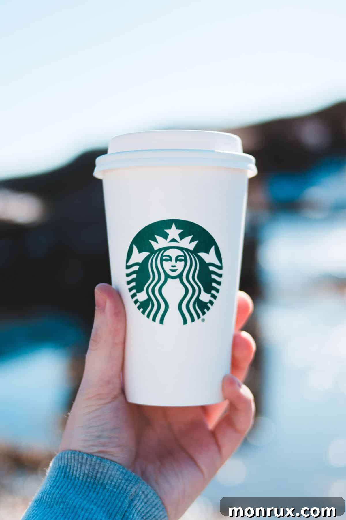 A person holding a Starbucks cup, featuring a variety of decaf and caffeine-free options available.