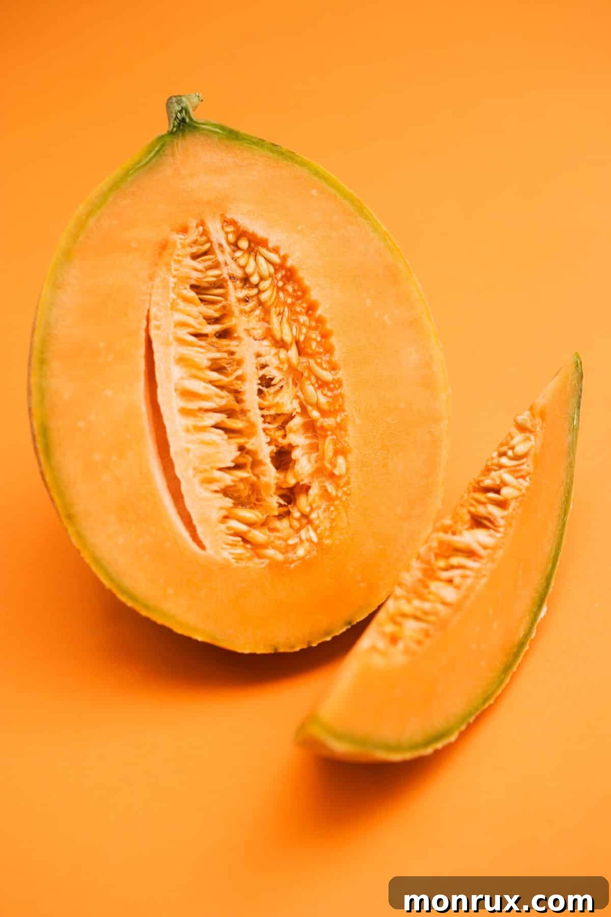 A vibrant, freshly sliced cantaloupe melon resting on a complementary orange background, showcasing its juicy, salmon-colored flesh and delicate texture.