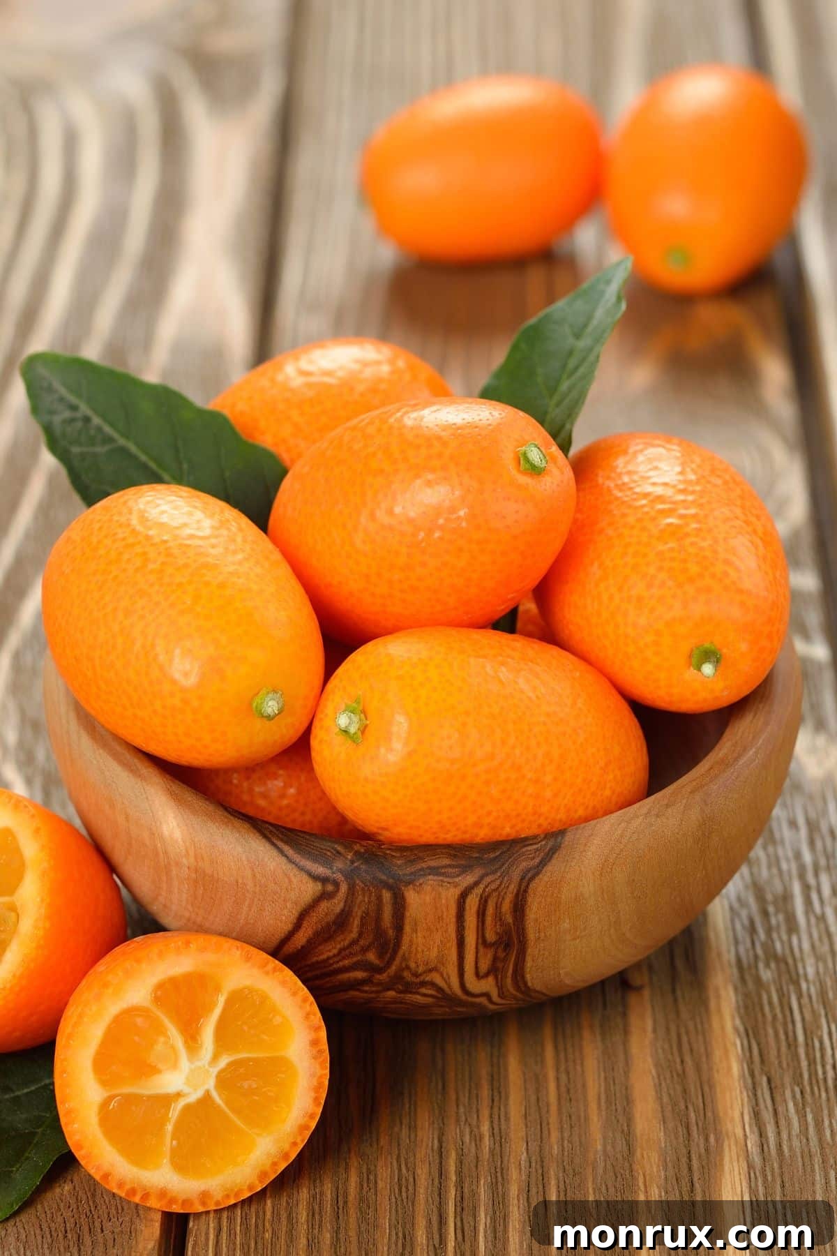 A rustic wooden bowl filled with a generous cluster of small, bright orange kumquats, showcasing their unique citrus charm.