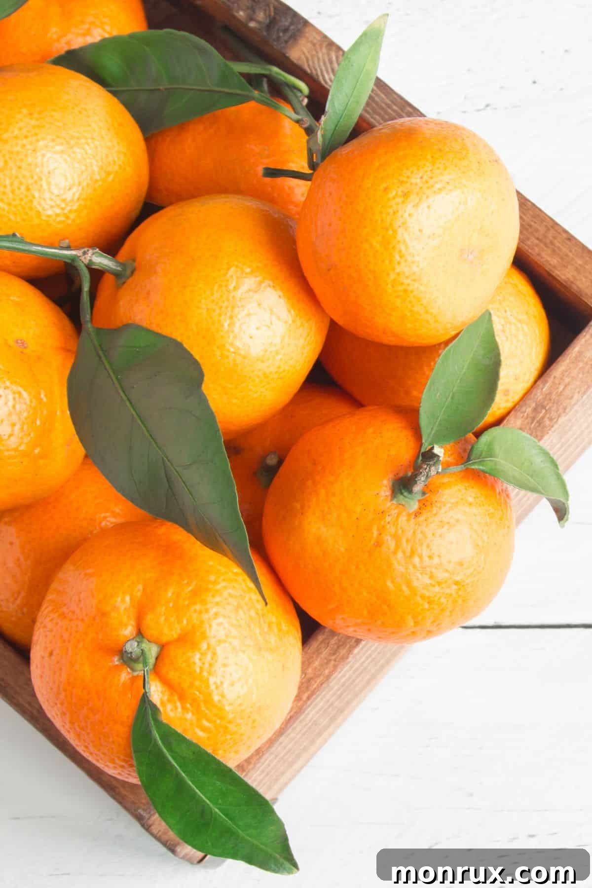 A charming wooden box overflowing with numerous bright orange tangerines, highlighting their appealing color and smooth texture.