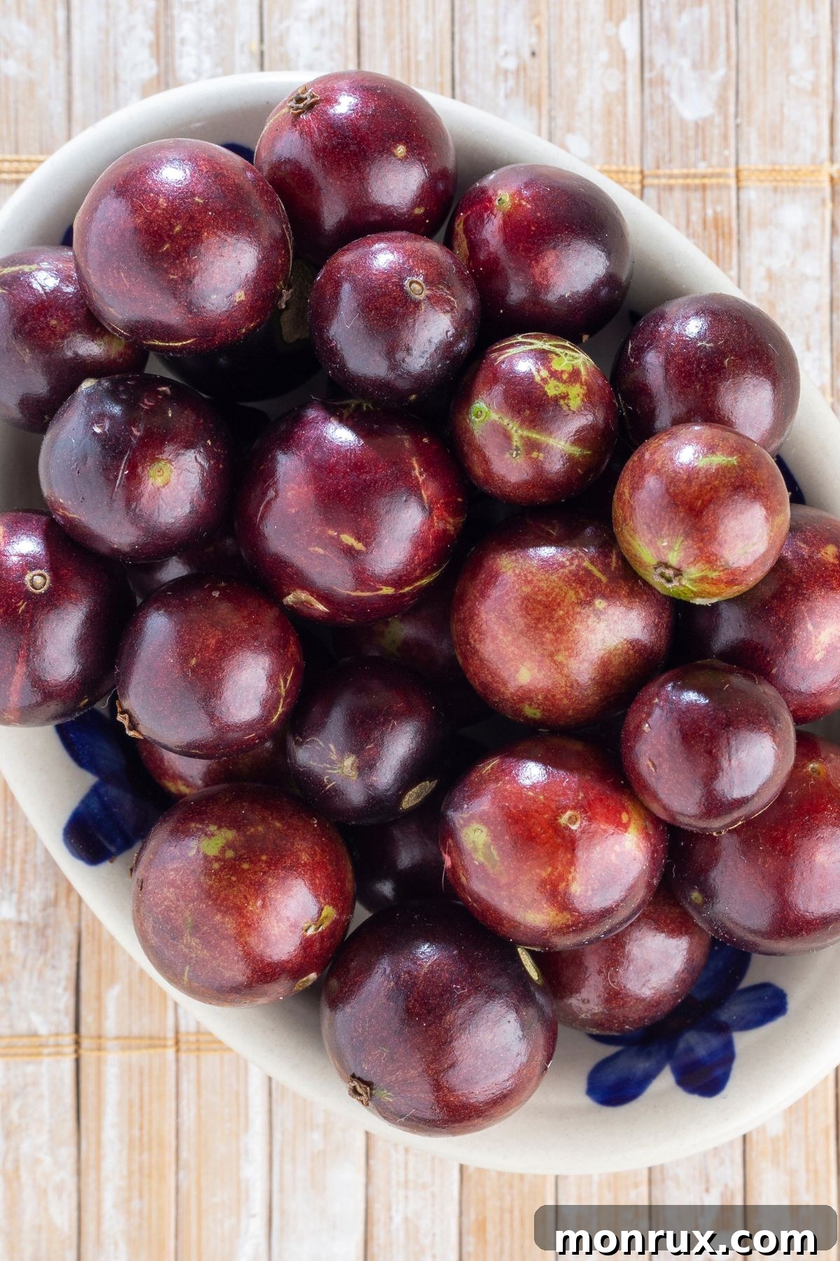 A bowl filled with dark, round Jaboticaba fruits, resembling large grapes.