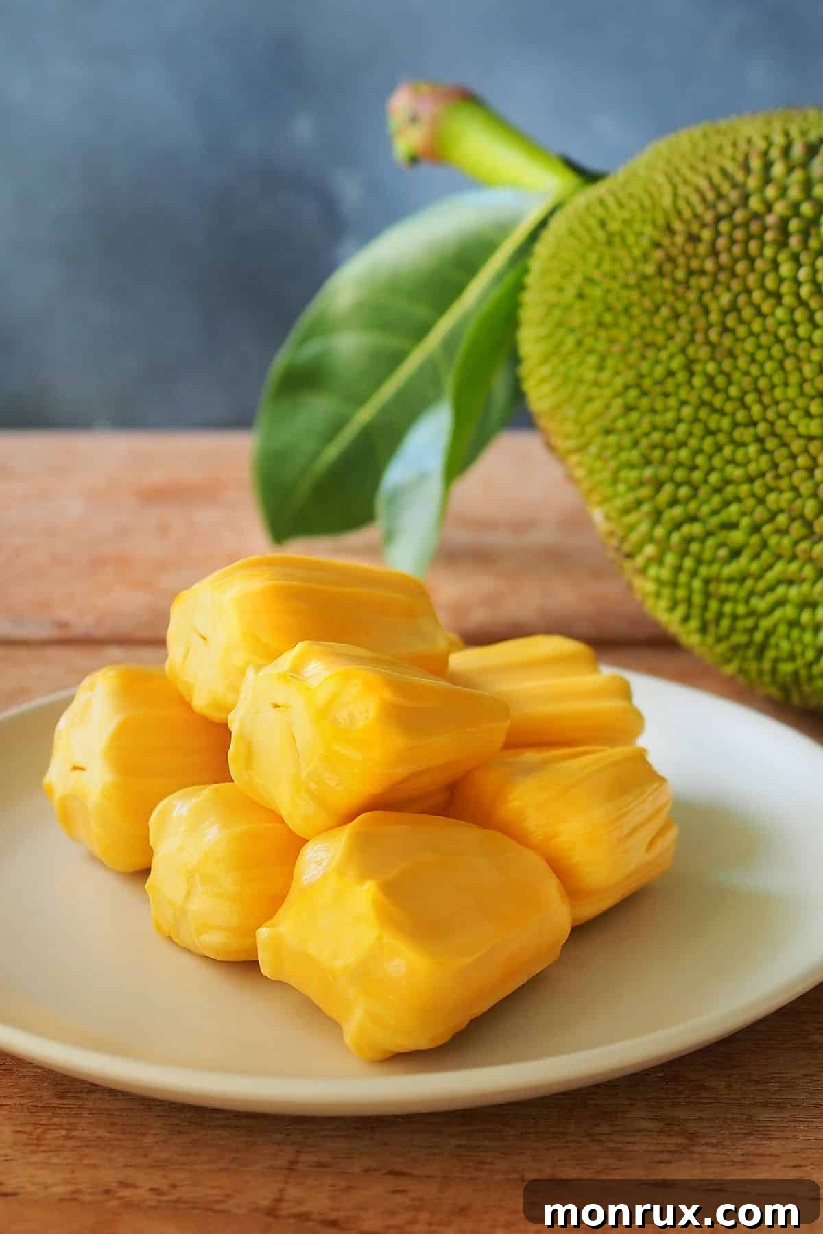 A white plate showcasing sliced ripe jackfruit, displaying its yellow, sweet flesh.