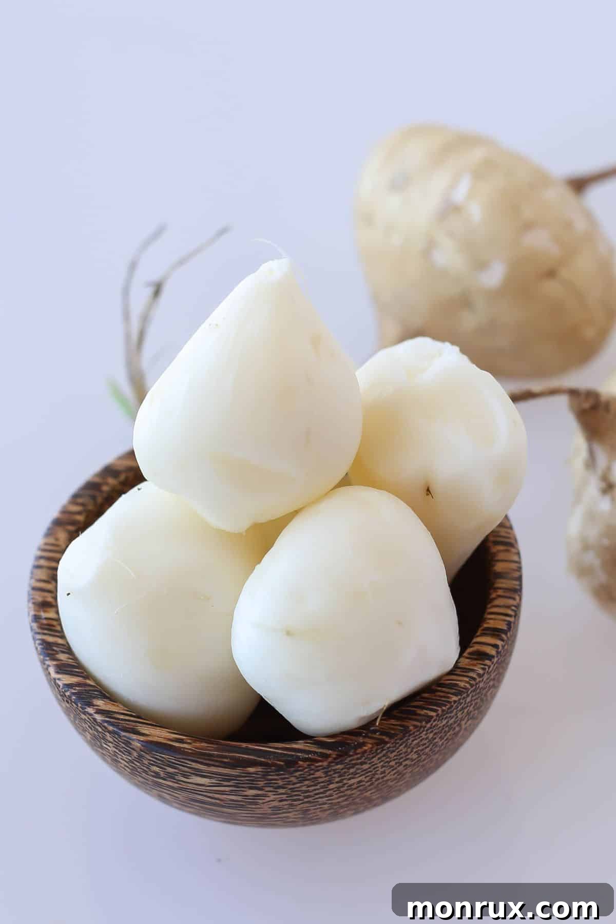 A wooden bowl generously filled with peeled and sliced jicama, showcasing its white, crisp flesh.