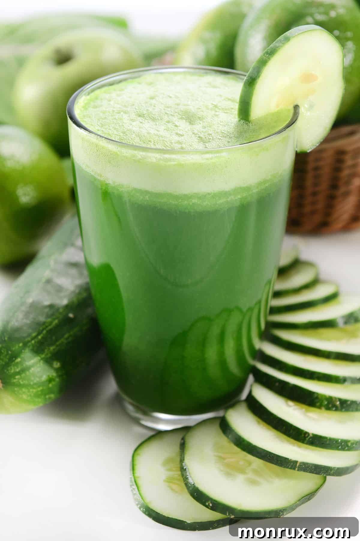 A short glass of green apple juice garnished with cucumber slices, signifying freshness and a delightful blend of flavors.