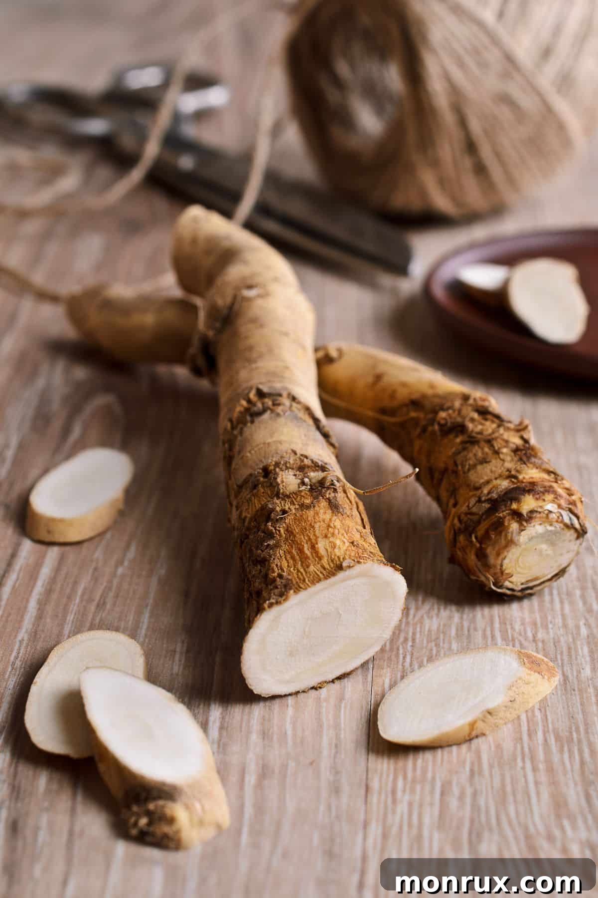 Freshly sliced horseradish root displayed on a textured wooden table, revealing its crisp white interior.