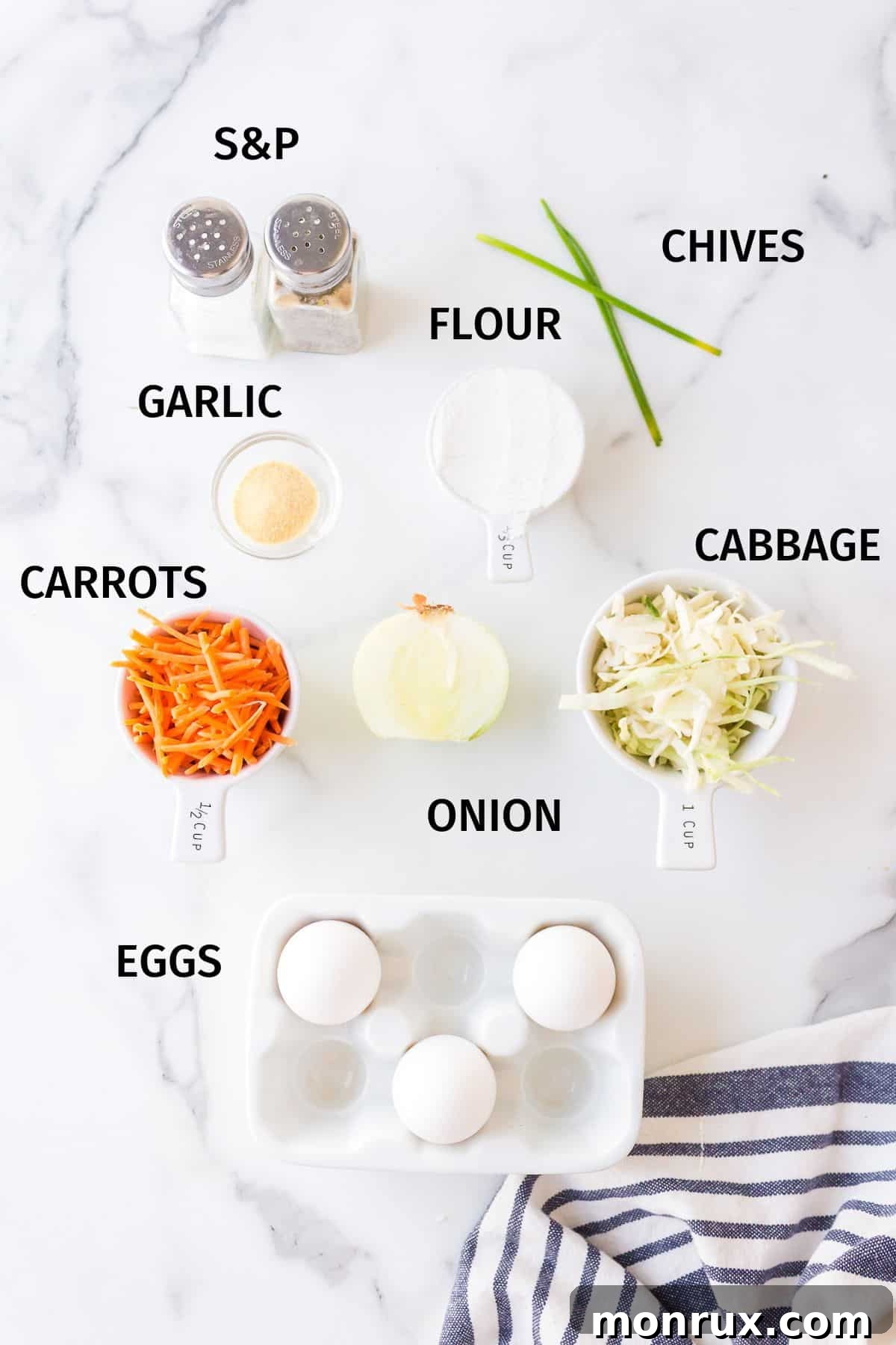 A collection of fresh ingredients for cabbage fritters, including shredded cabbage, carrots, onion, eggs, flour, and seasonings, arranged neatly in small bowls on a pristine white surface.