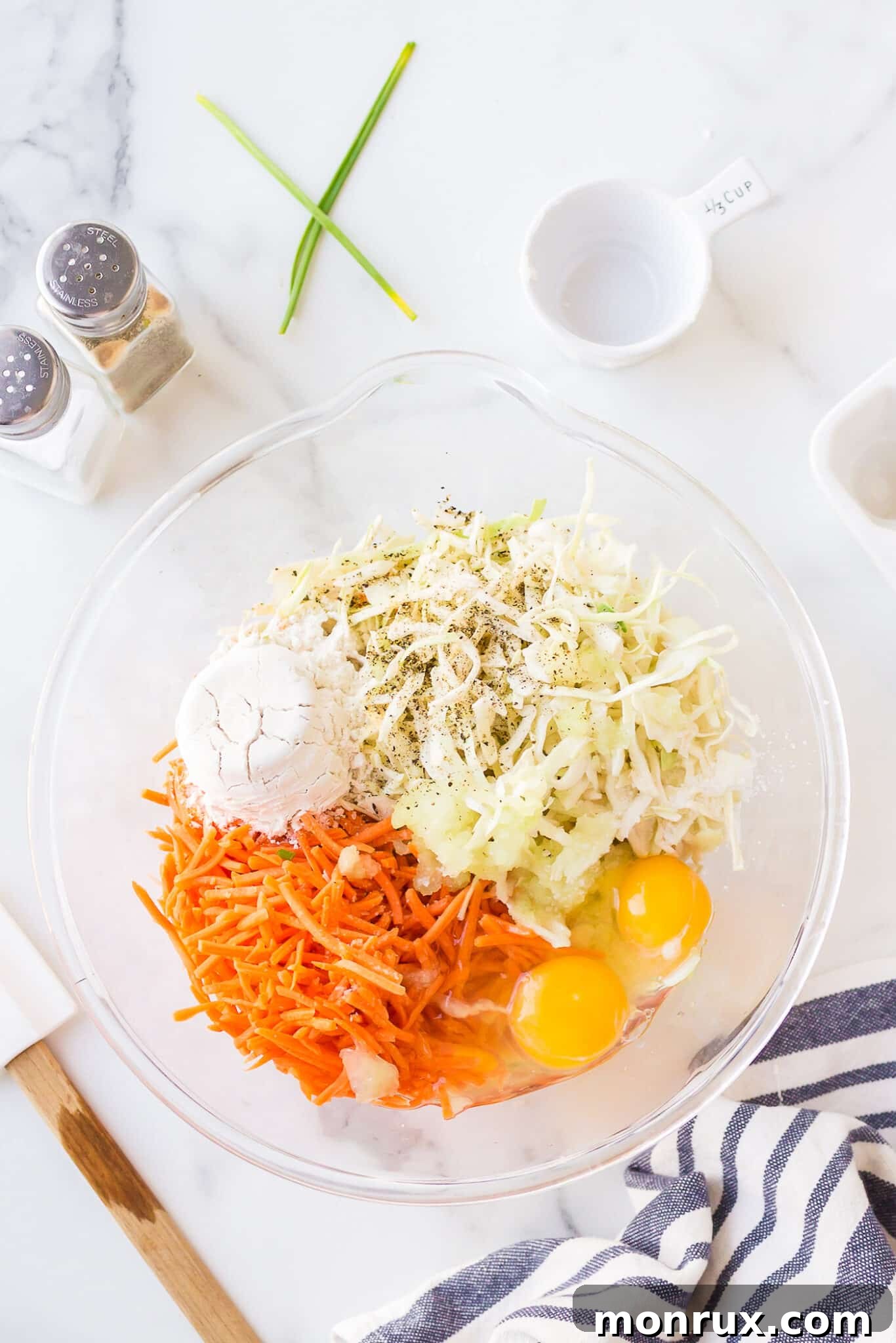 All the shredded cabbage, carrots, onion, eggs, flour, and seasonings neatly combined in a large mixing bowl.